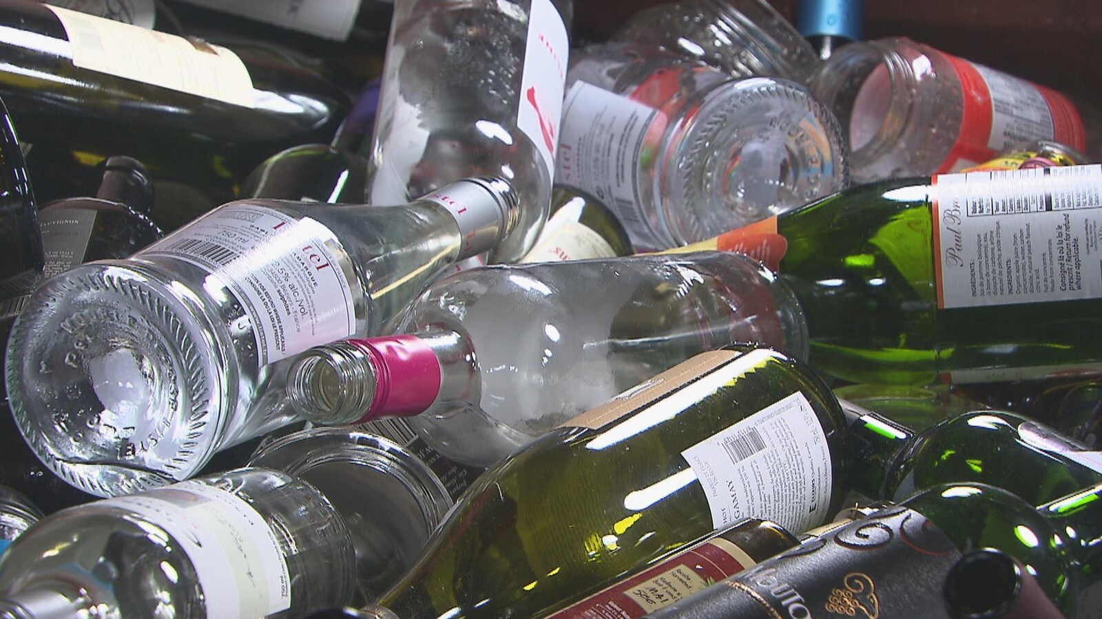 Des bouteilles de vin et autres contenants en verre empilés les uns par dessus les autres.