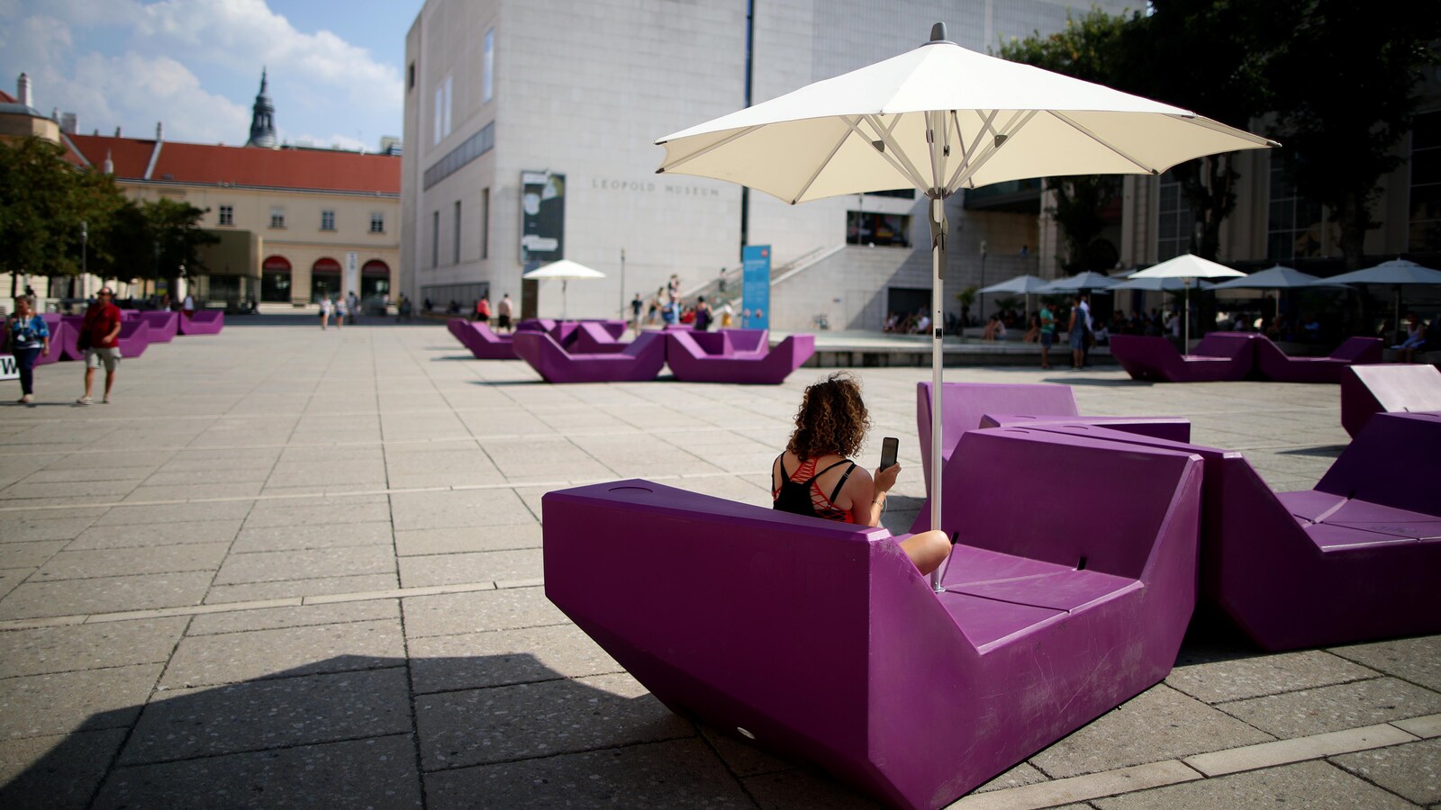 Une femme est assise à l'ombre au centre du MuseumsQuartier de Vienne, en Autriche.