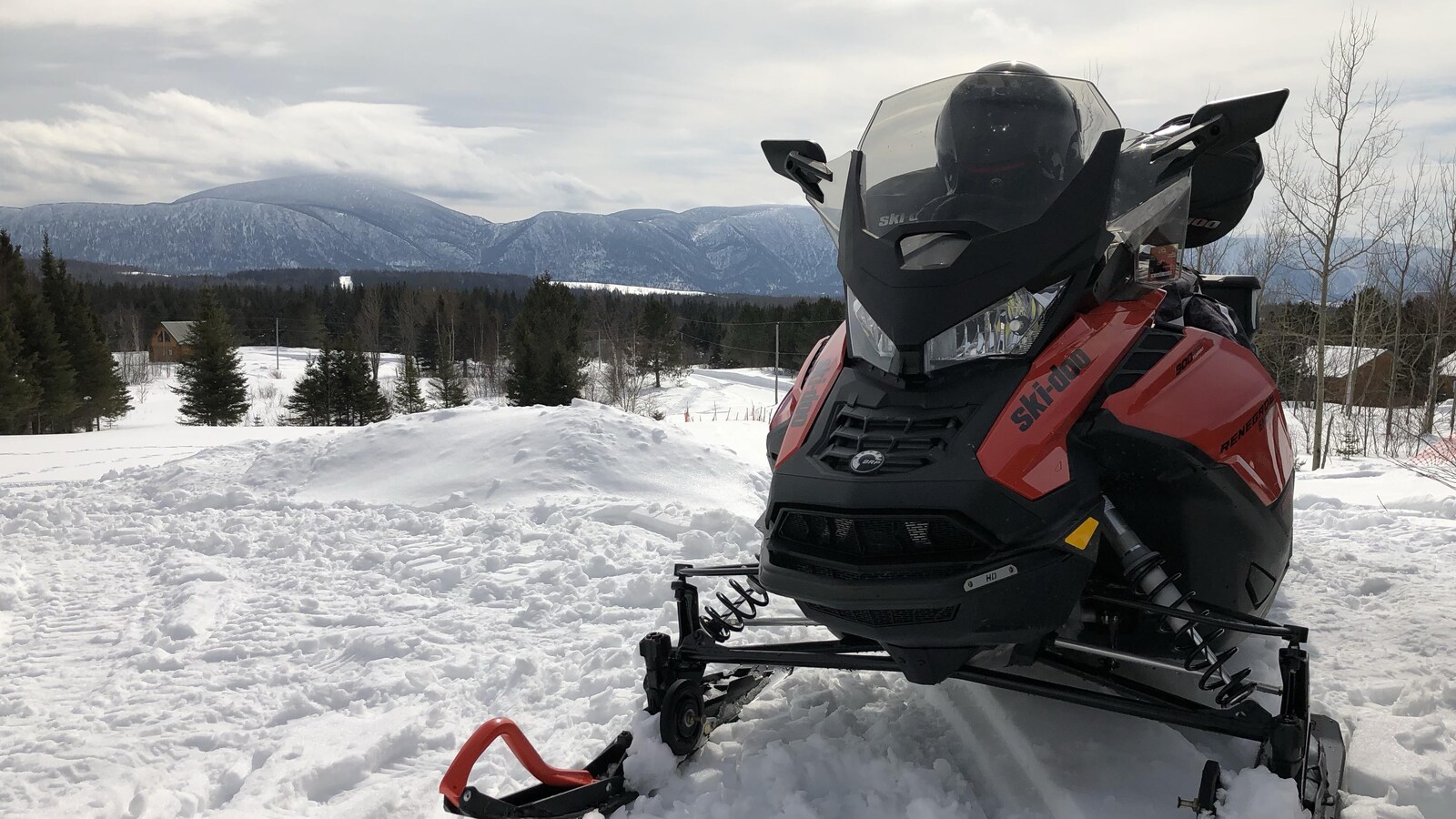 Motoneigiste à l'avant-plan, montagnes magnifiques derrière.