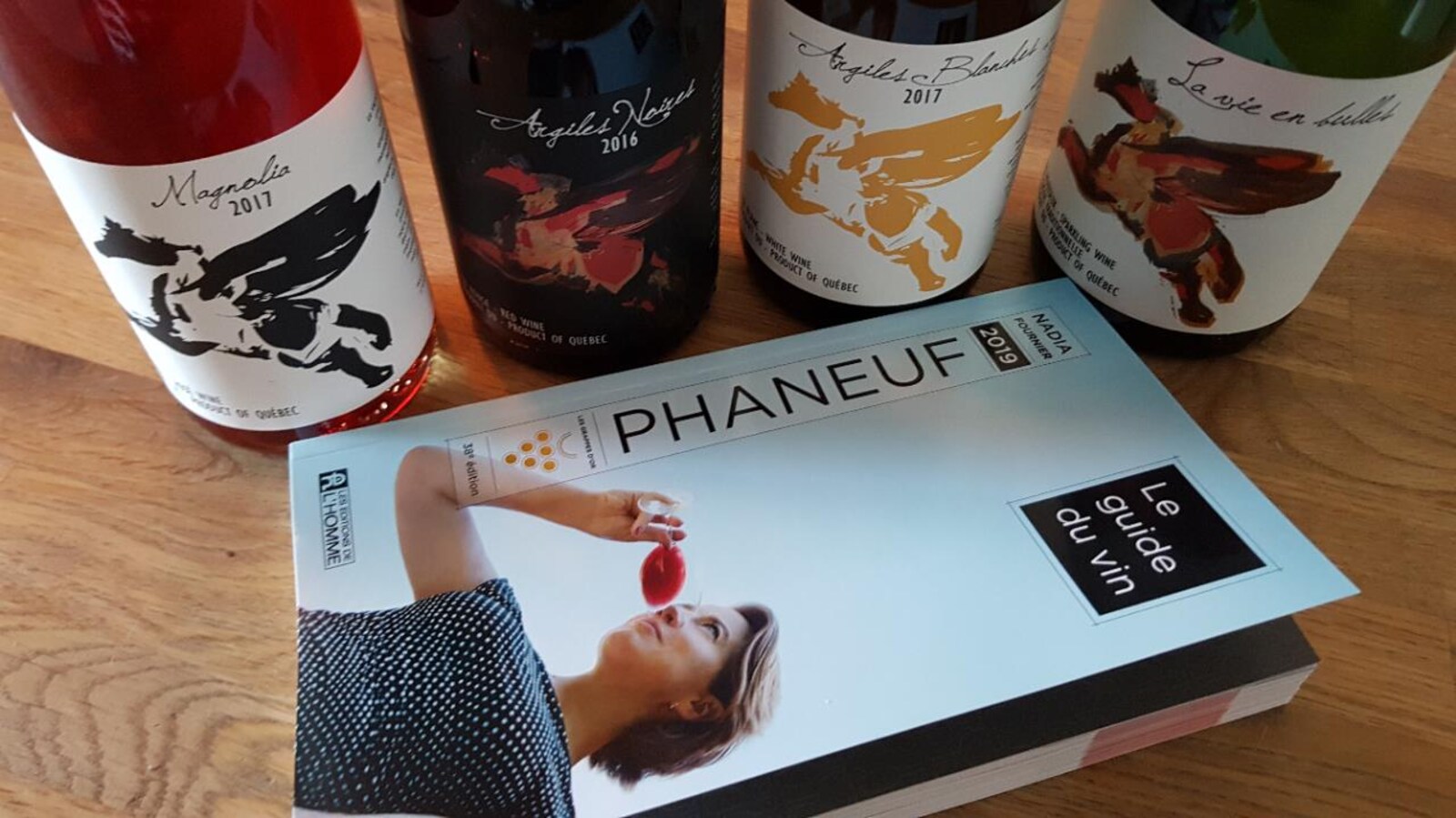 Quatre bouteilles de vin posées derrière un guide de vin.