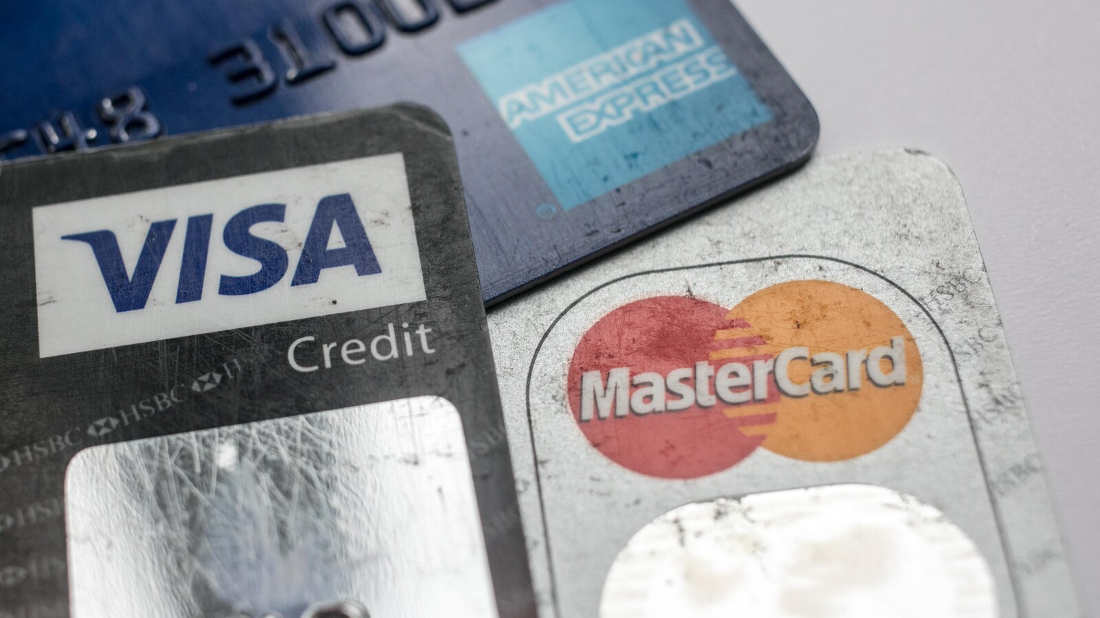 Trois cartes sur lesquelles on peut lire Visa, MasterCard et American Express sont photographiées sur une table. Elles sont vues de très près.