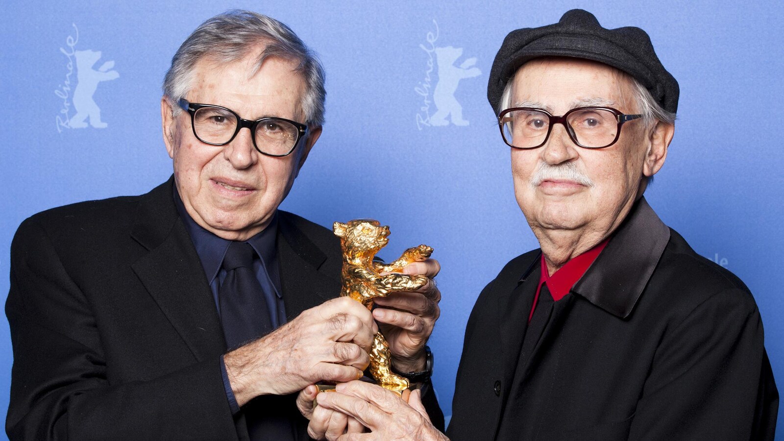 Les réalisateurs Paolo et Vittorio Taviani posent ensemble devant un fond bleu.