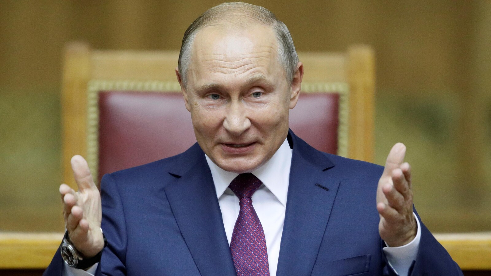 Le président russe Vladimir Poutine gesticule assis dans un fauteuil.