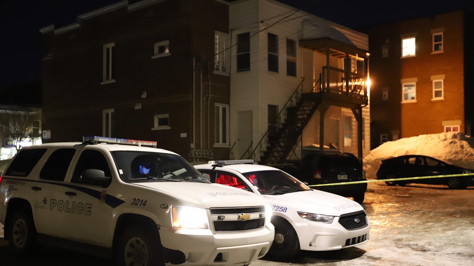 Deux véhicules de police devant un immeuble résidentiel du quartier Limoilou.