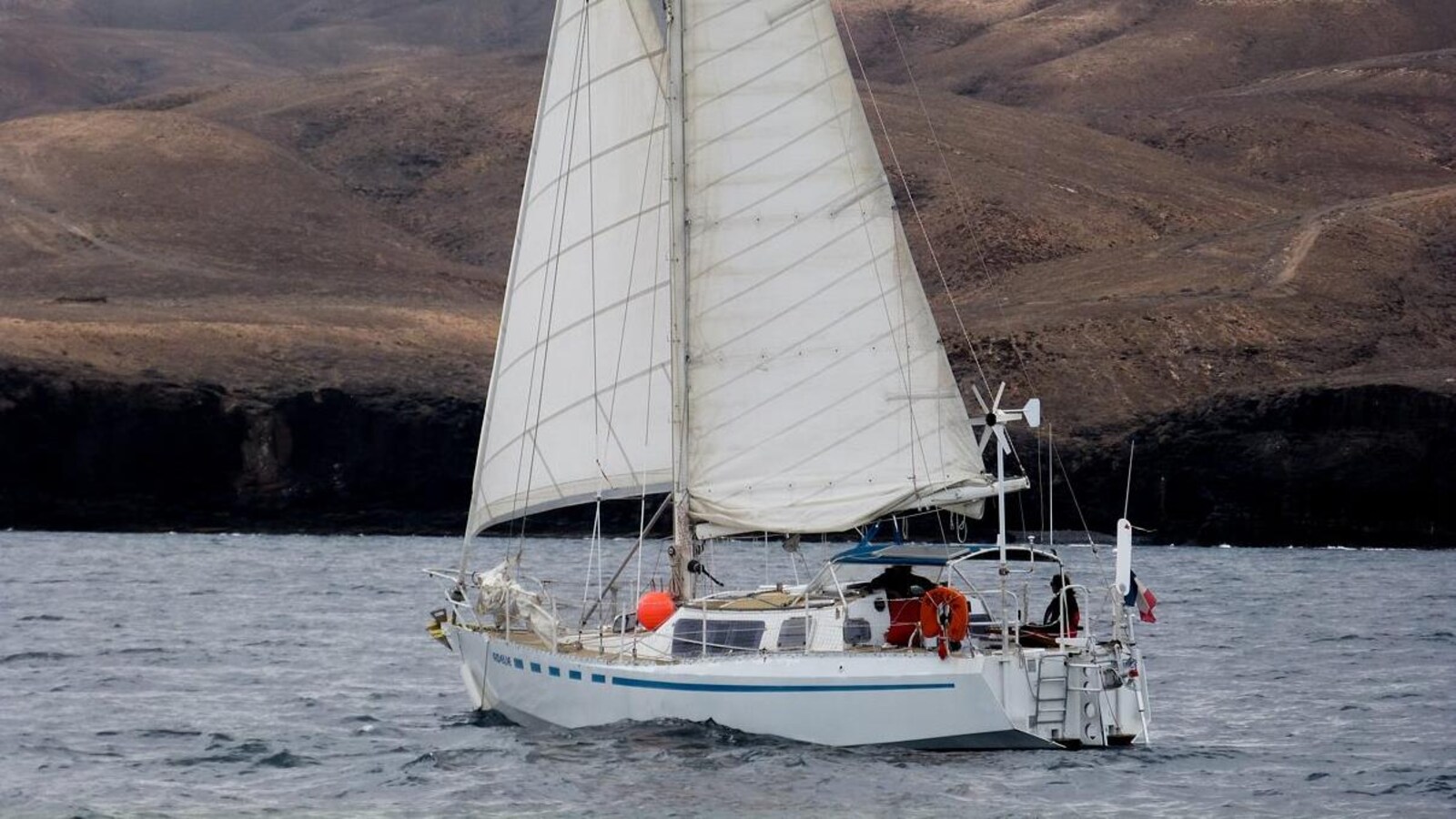 Un voilier équipé d'un panneau solaire vogue au large d'une île.