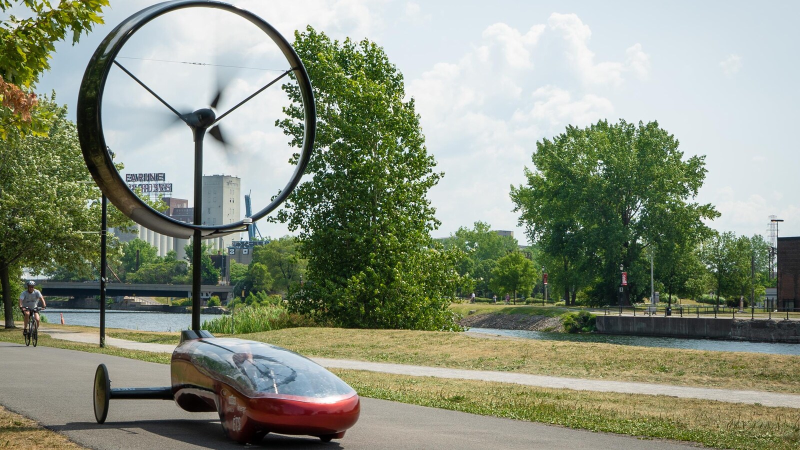 Elle avance devant un vélo sur une piste cyclable en bordure de l'eau.