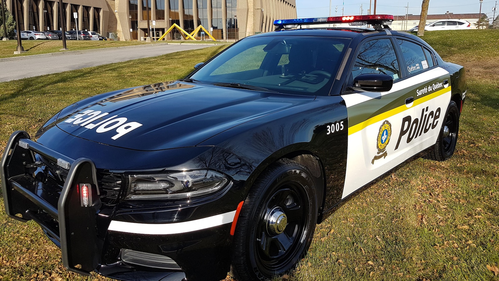 Nouvelle voiture de police de la Sûreté du Québec sur un terrain devant une station