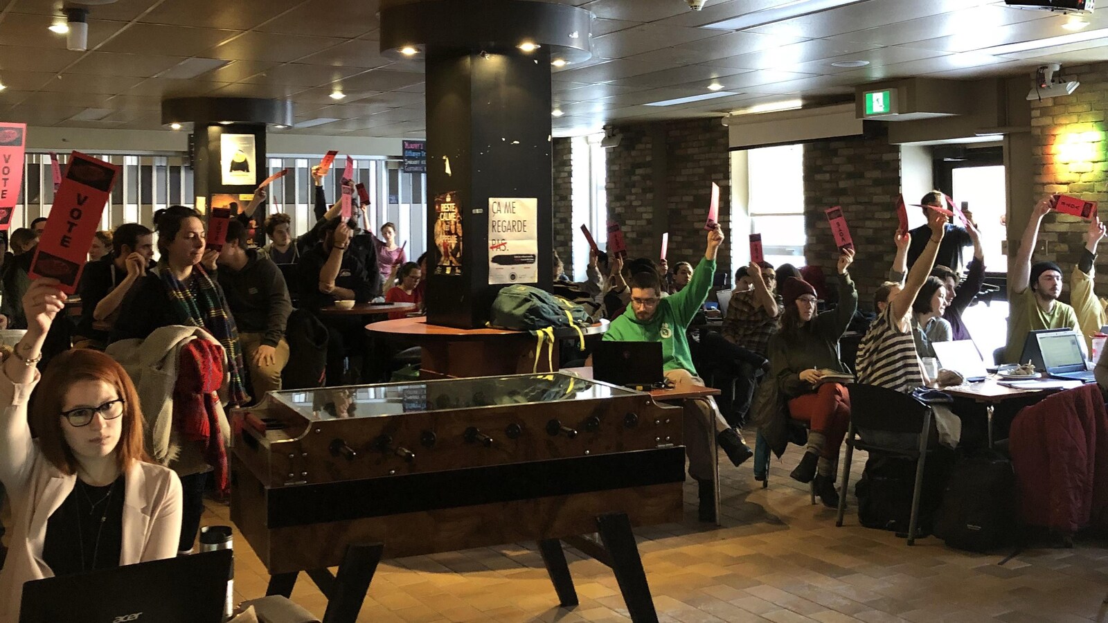 Des étudiants tiennent des cartons de vote en l'air.