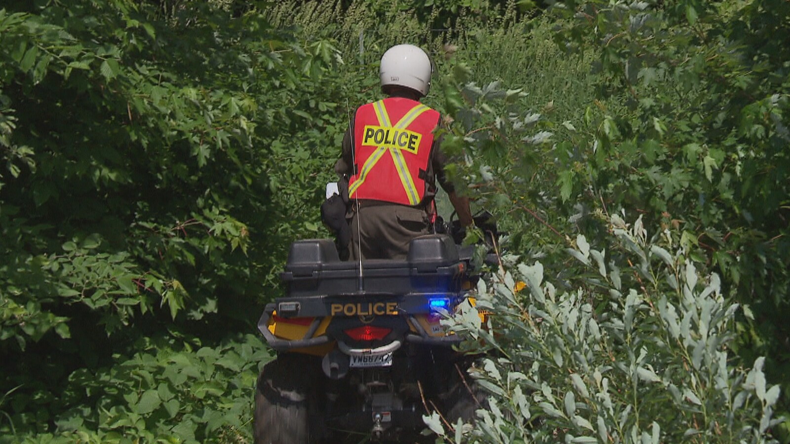 Policier sur un VTT dans un boisé