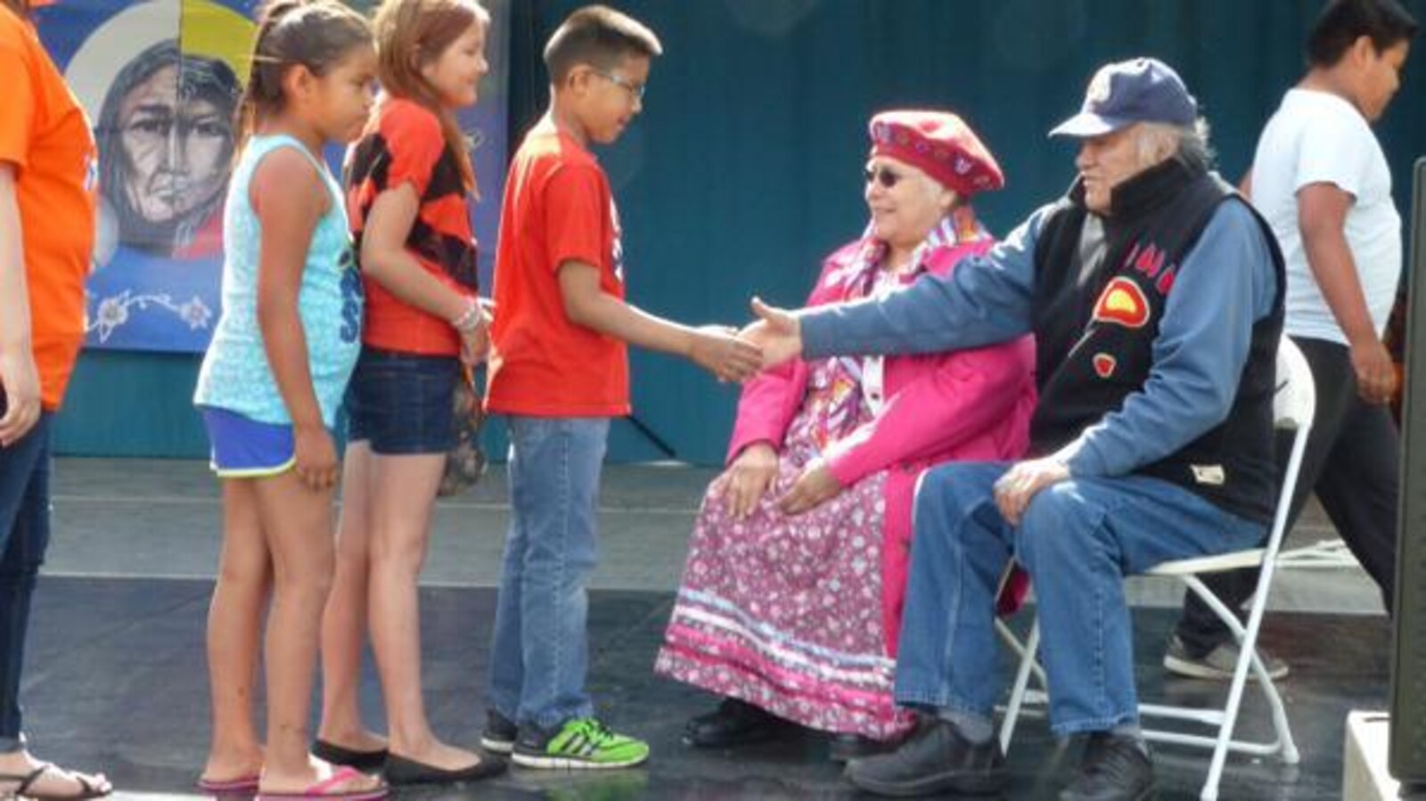 Walter Linklater et sa femme serrent les mains d'enfants.