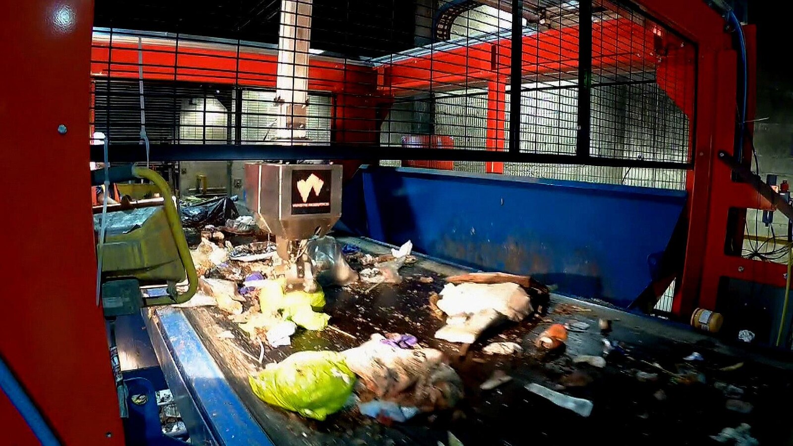 Le bras articulé du robot créé par Waste Robotics s'apprête à cueillir un sac vert rempli de restes de table.