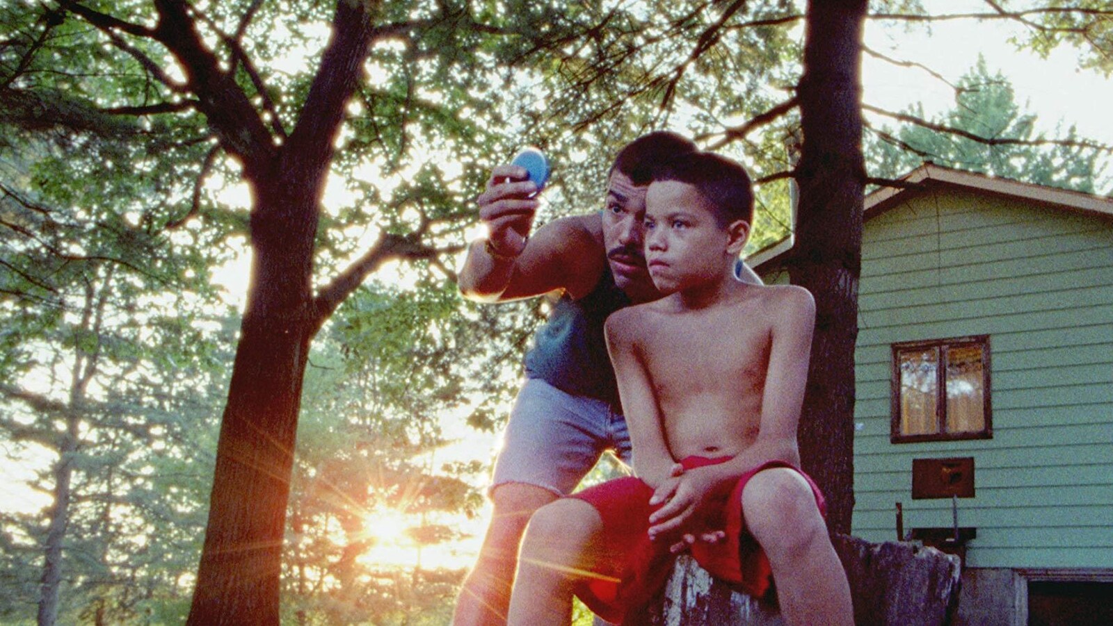 Image tirée du film <em>We the Animals</em> montrant les acteurs Raúl Castillo et Evan Rosado se tenant devant une maison située dans un secteur boisé.