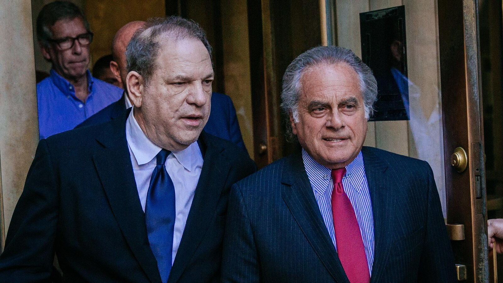 Deux hommes portant des vestons et des cravates discutent en sortant d'un bâtiment.
