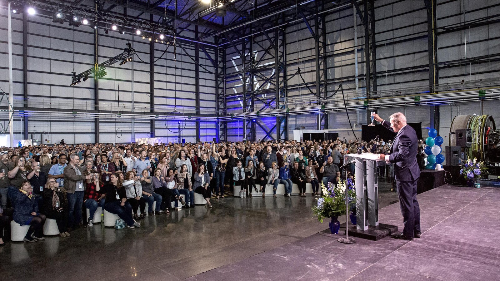 Ed Simms lève son verre au nouveau hangar, devant la foule.