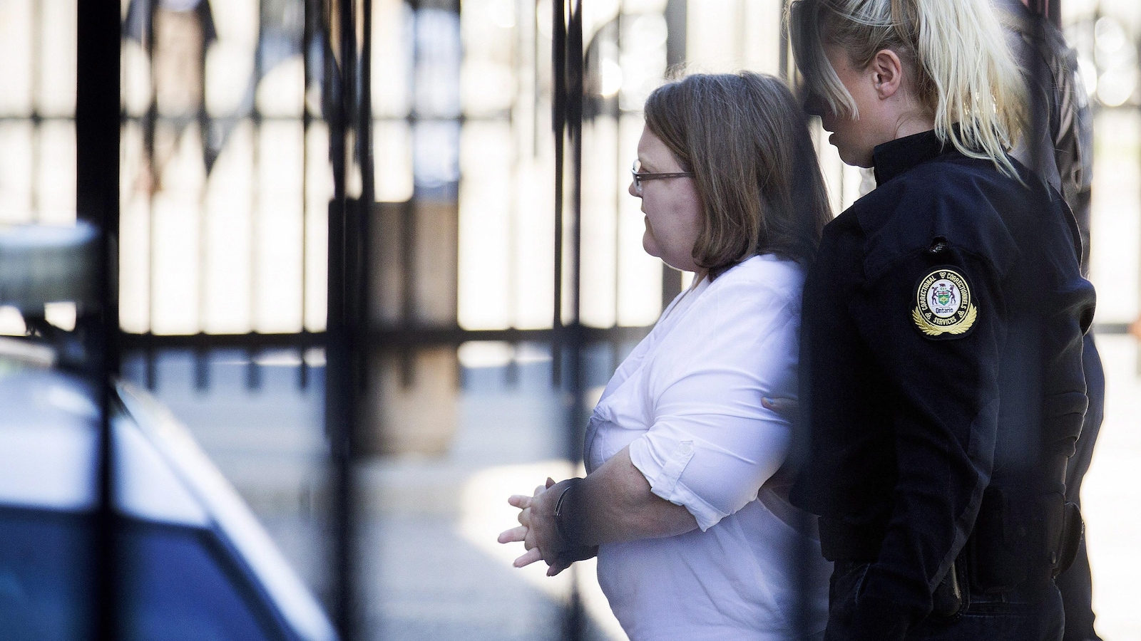 Photo de Wettlaufer qui est suivie par une policière alors qu'elle se dirige vers le tribunal.