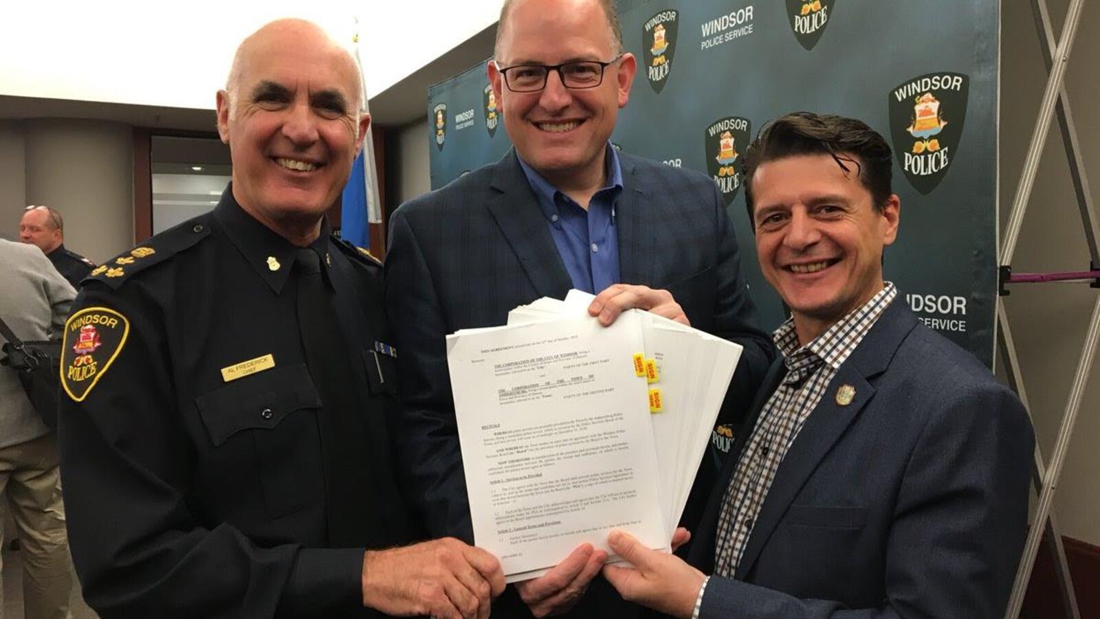 Trois hommes avec des papiers dans les mains.