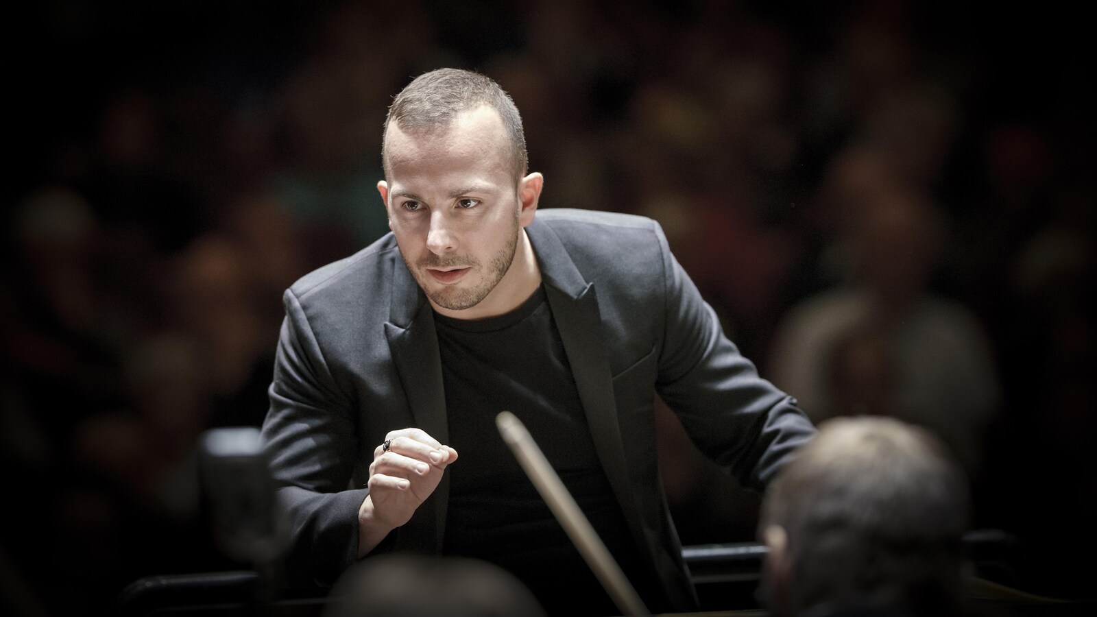 Le regard concentré, le chef d'orchestre dirige à la main son ensemble.
