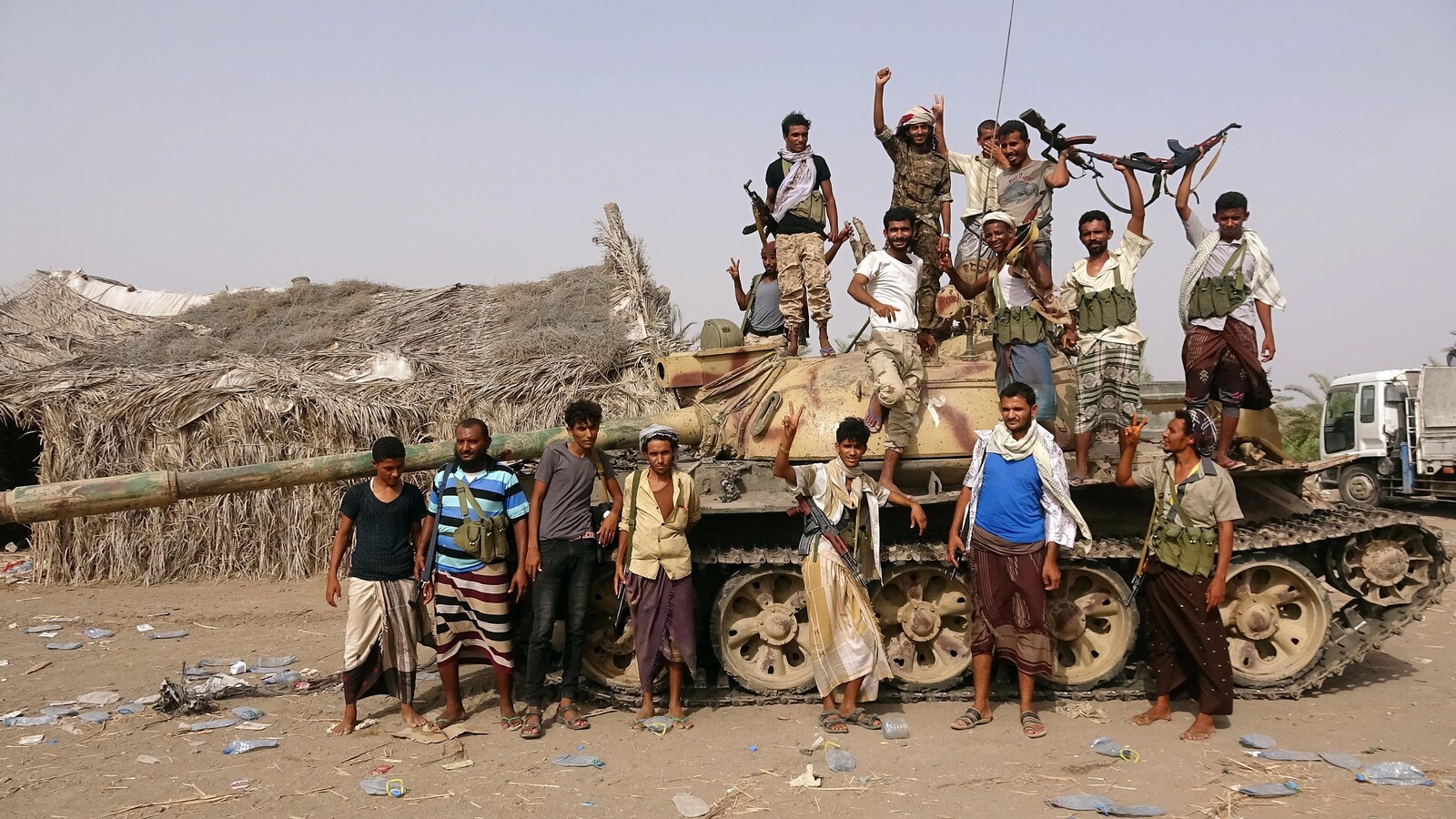 Une dizaine d'hommes en tenue traditionnelle se tiennent debout devant et dessus un tank. Certains brandissent des armes.