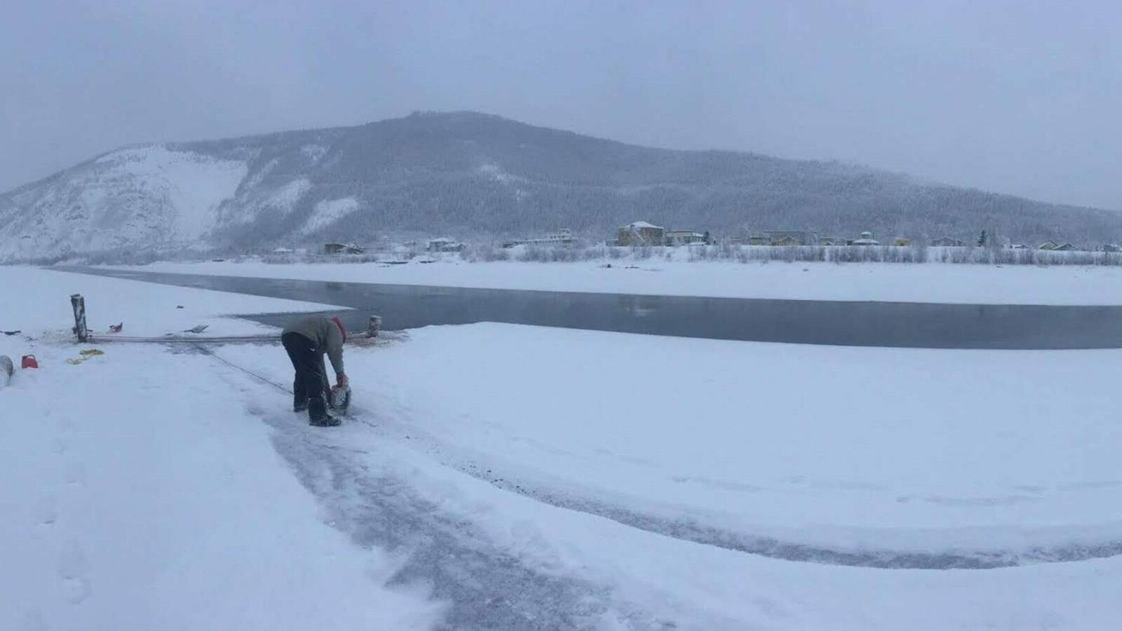 Un homme penché découpe de la glace dans l'eau.