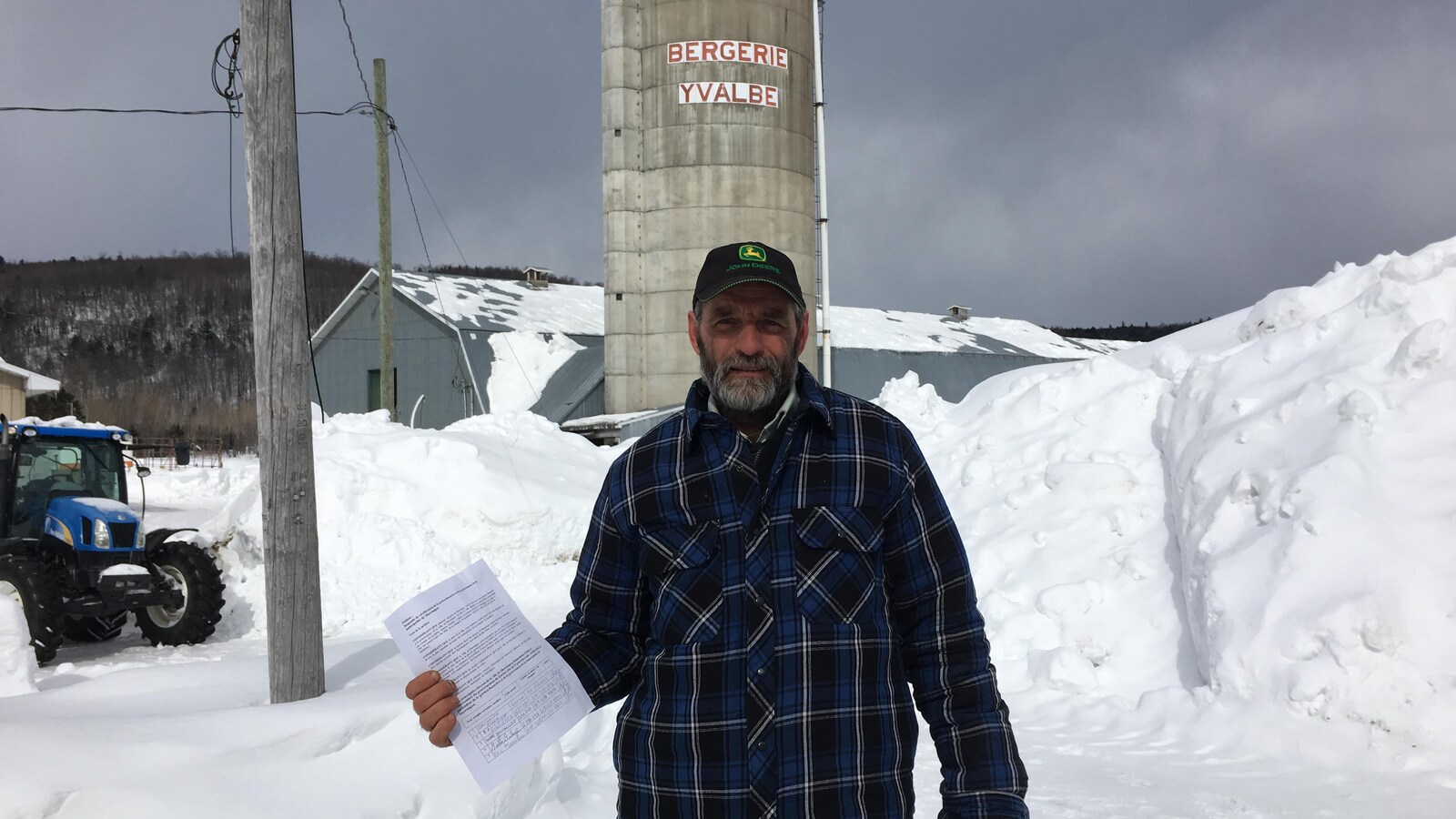 Yves Gélinas avec la pétition dans les mains devant un silo de grains