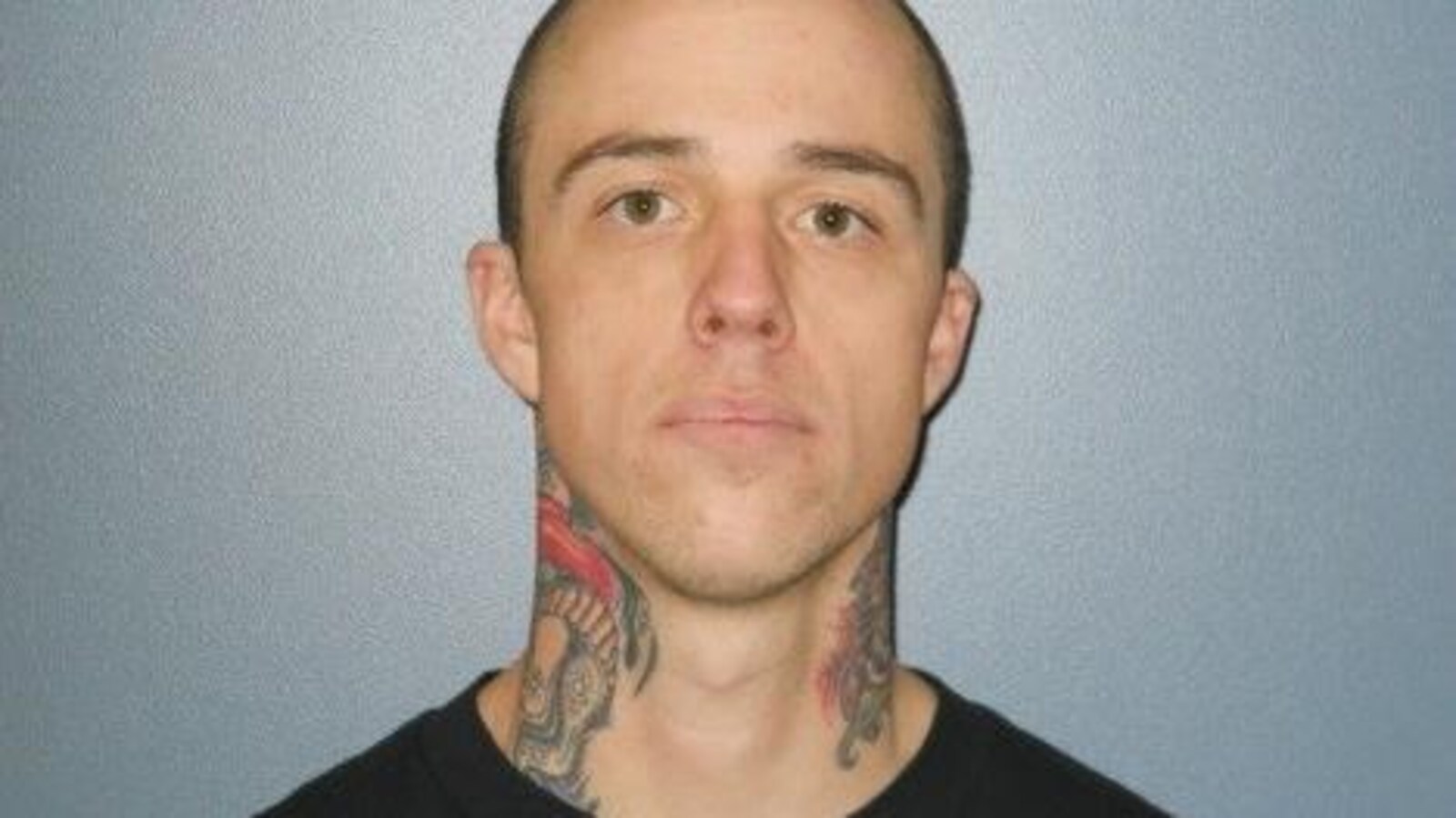 Un portrait du fugitif, avec des tatouages dans le cou.