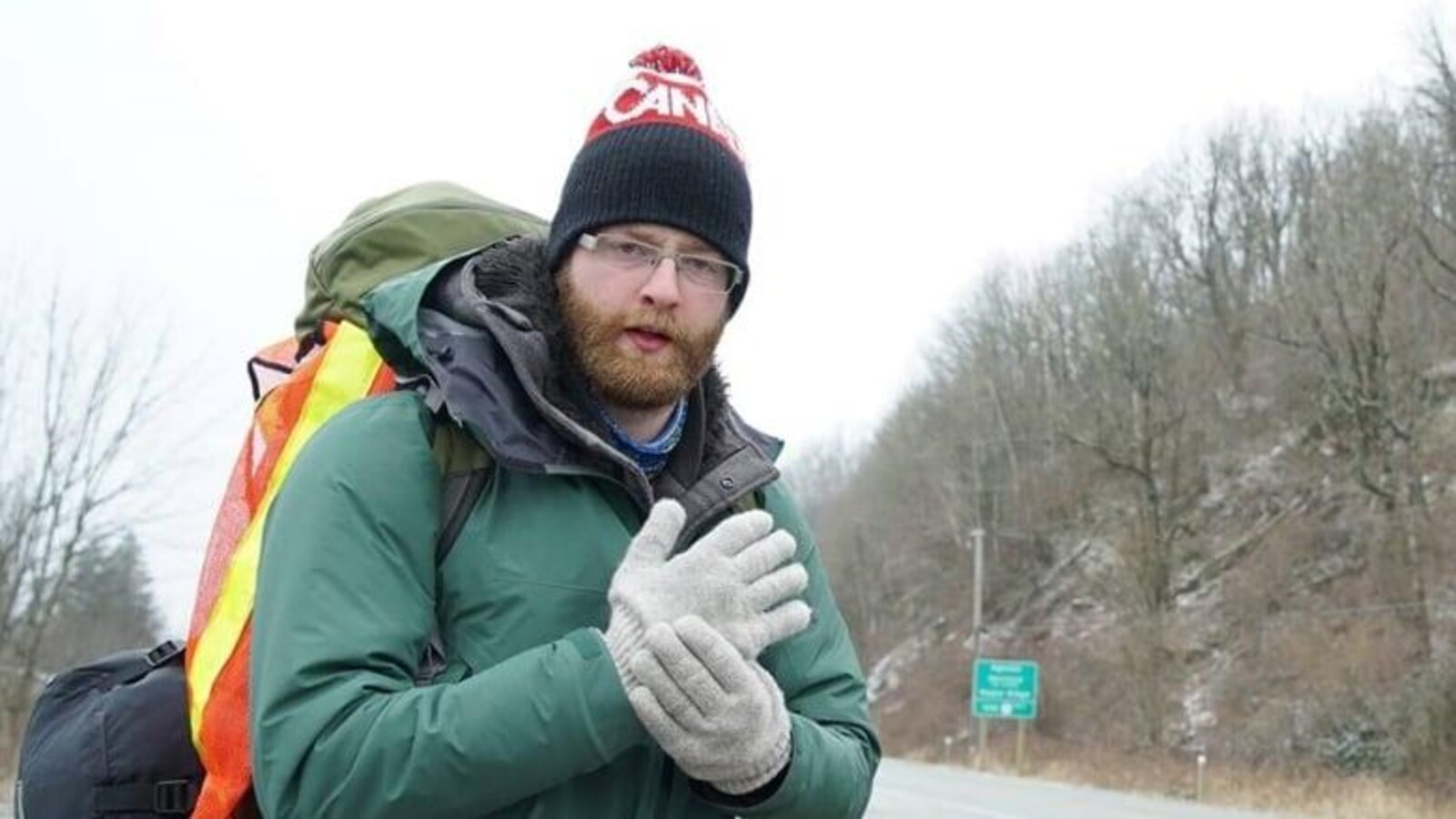 Zayell Johnston, en tenue d'hiver, portant son sac au dos, debout près d'une route.