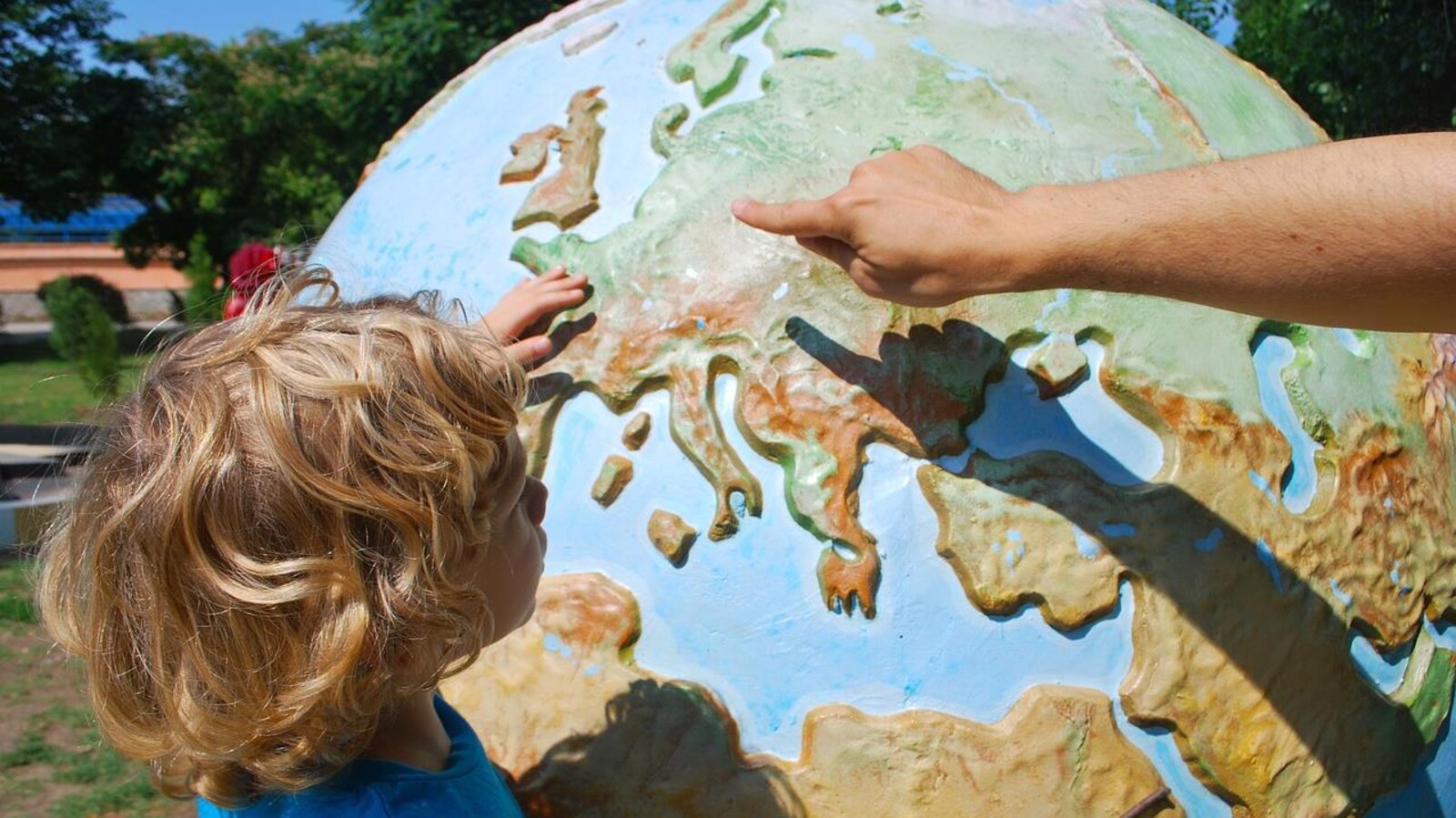 Un enfant regarde la planète terre avec un adulte à ses côtés.