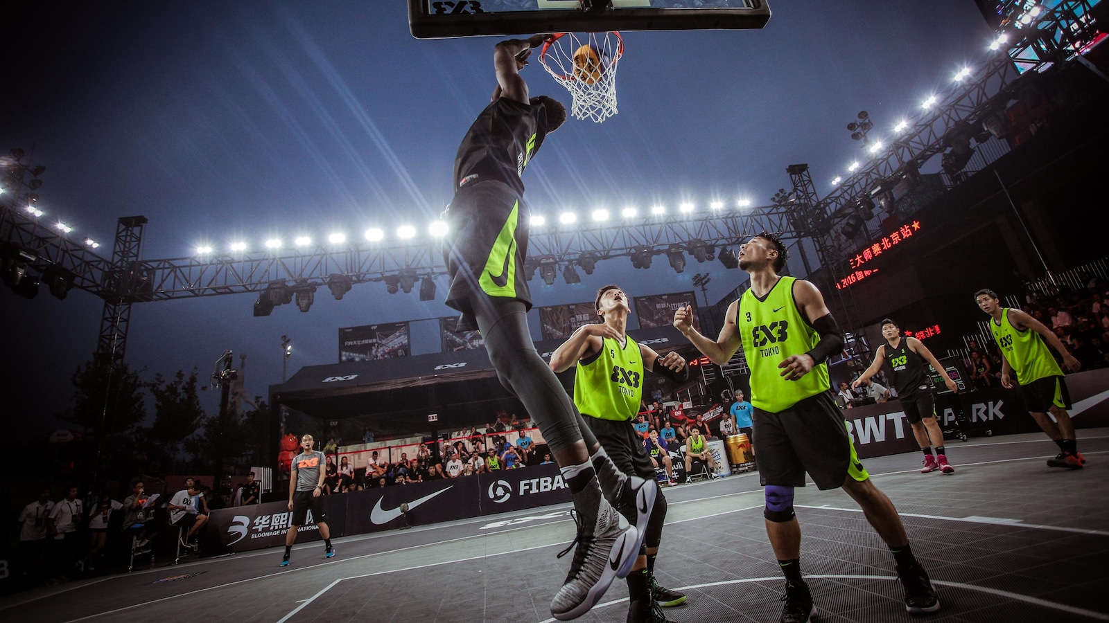 Un joueur de basketball 3 contre 3 réussit un panier devant deux adversaires qui assistent impuissants à la scène.