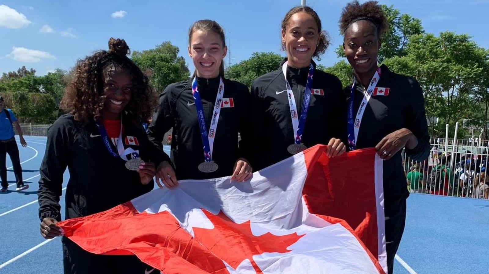 Quatre jeunes femmes posent avec un drapeau du Canada après une course.