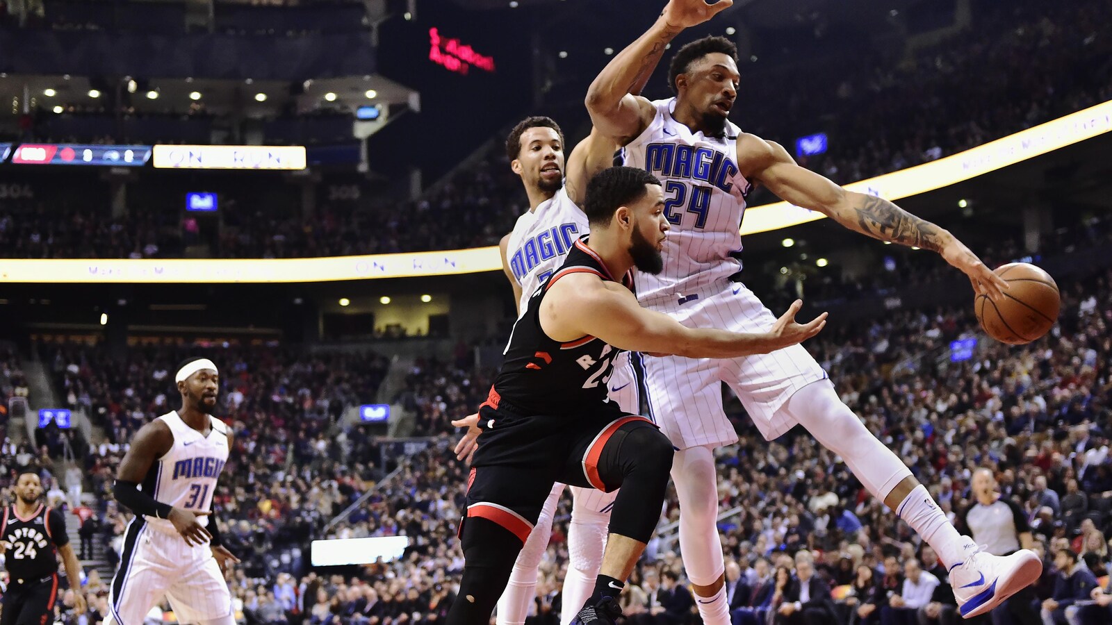 Fred VanVleet (à l'avant) tente une passe à un coéquipier des Raptors de Toronto devant Khem Birch (à droite) et Michael Carter-Williams, du Magic d'Orlando.
