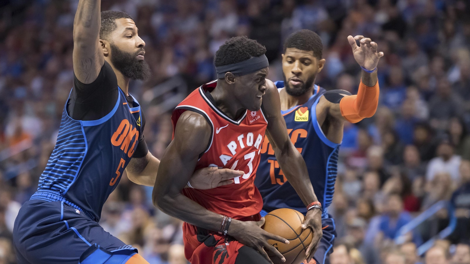 Pascal Siakam (au centre), des Raptors de Toronto, tente une percée au panier entre Markieff Morris (à gauche) et Paul George, du Thunder d'Oklahoma City.