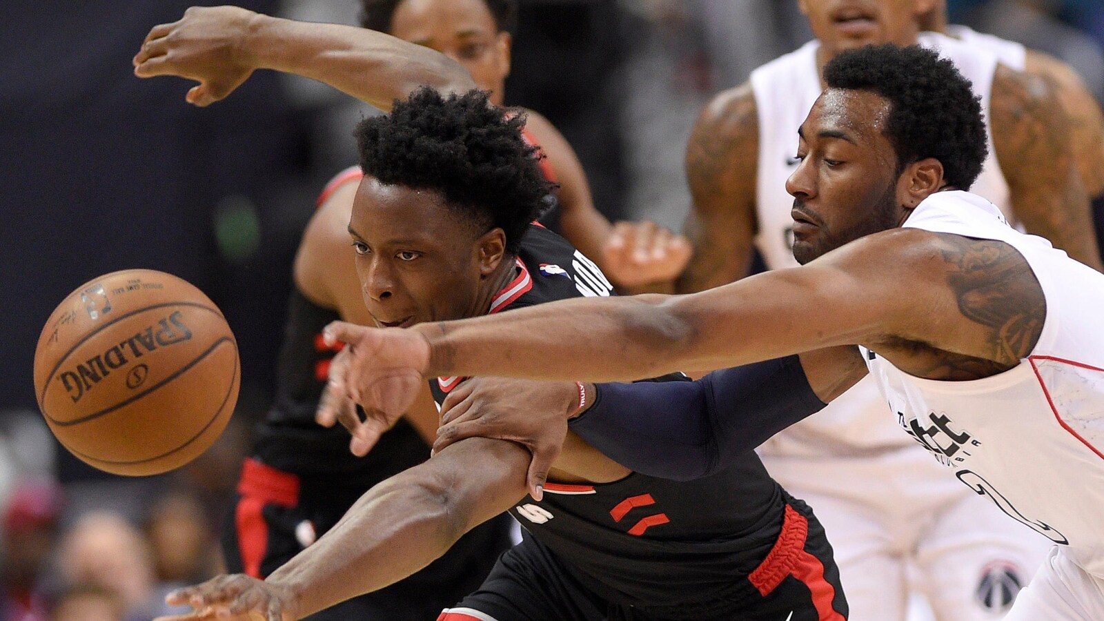 OG Anunoby (à gauche), des Raptors de Toronto, et John Wall, des Wizards de Washington, tentent de s'emparer du ballon.