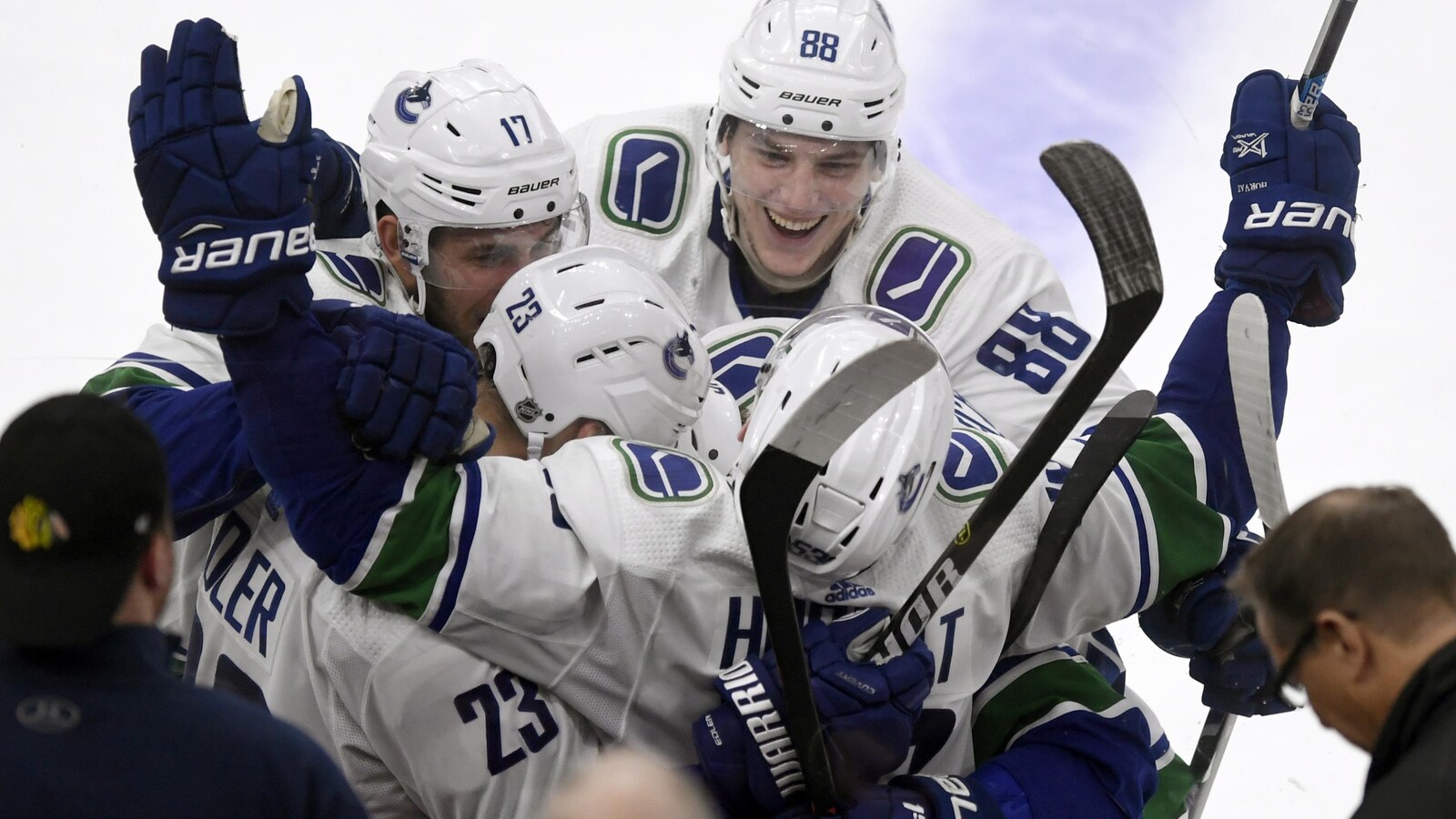 Il est entouré des autres joueurs sur la glace.