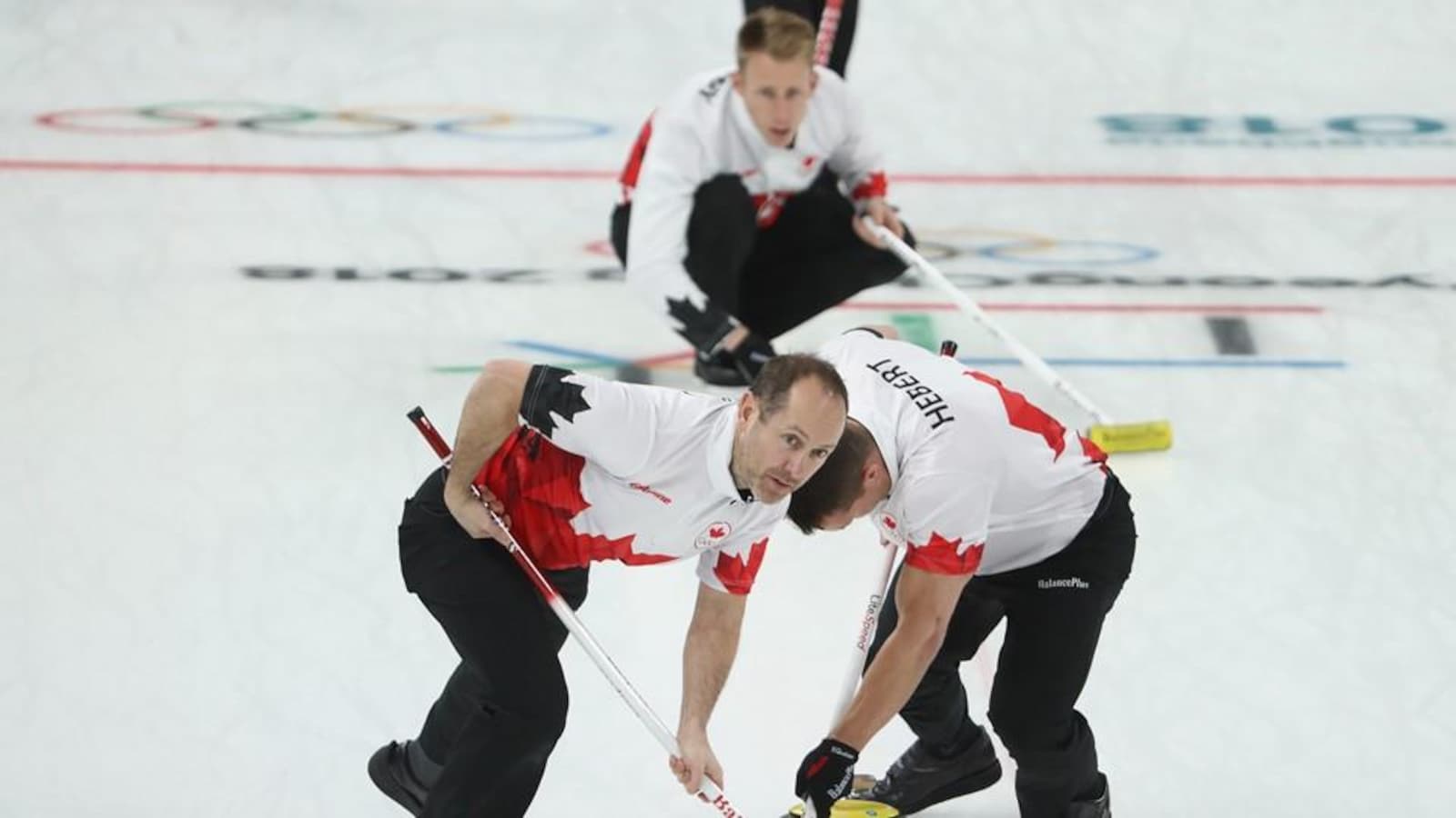 Trois hommes pratiquent le curling
