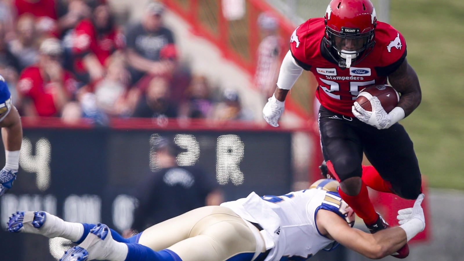 Taylor Loffler des Blue Bombers tente d'arrêter Don Jackson des Stampeders, qui court avec le ballon.