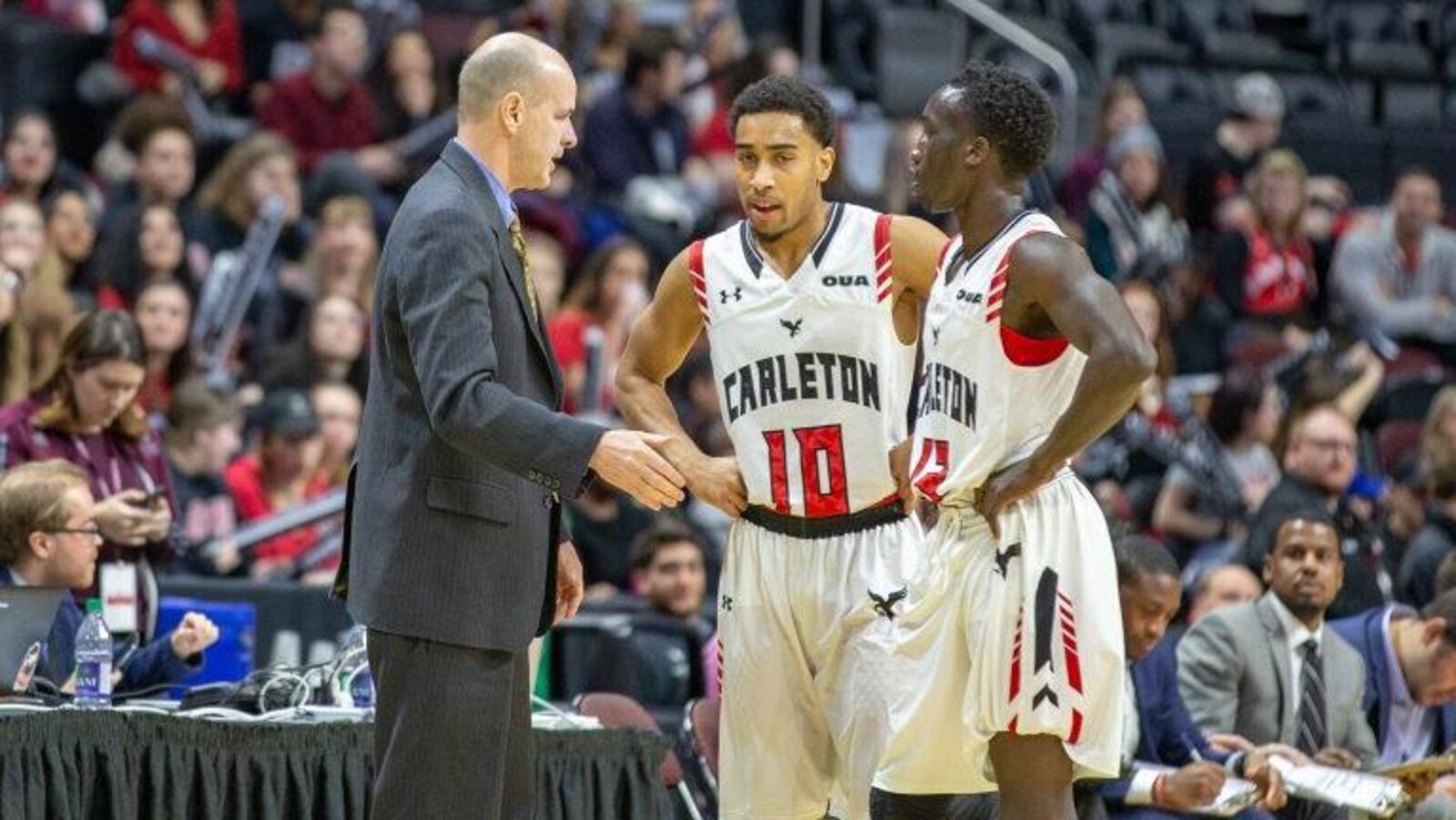 Un entraîneur s'adresse à deux joueurs sur un terrain de basketball