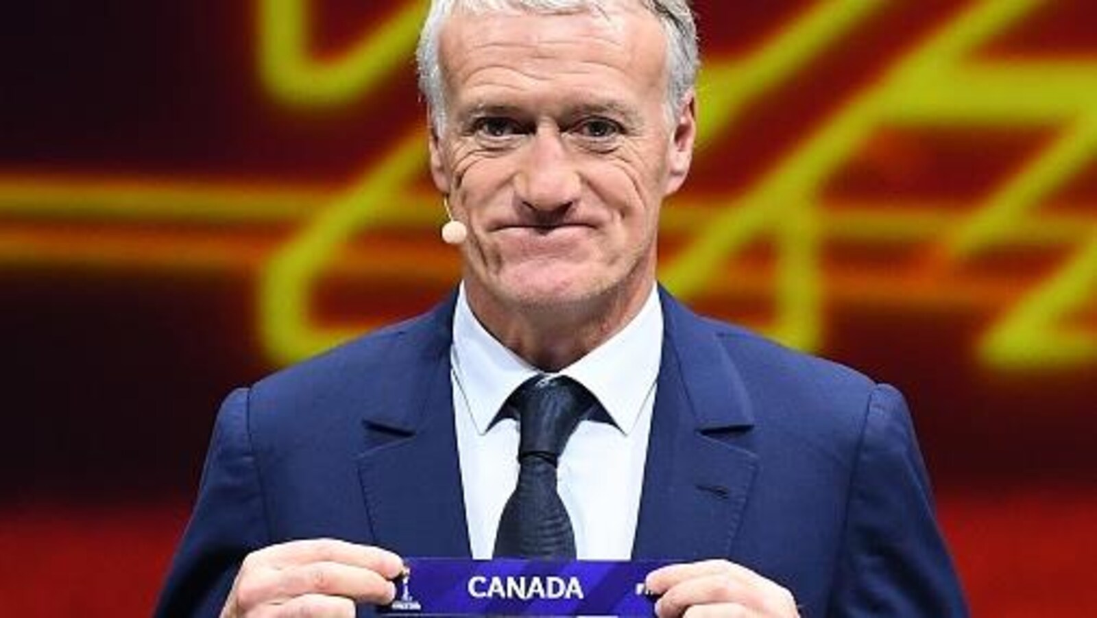 Il tient du bout des doigts l'affichette du Canada.