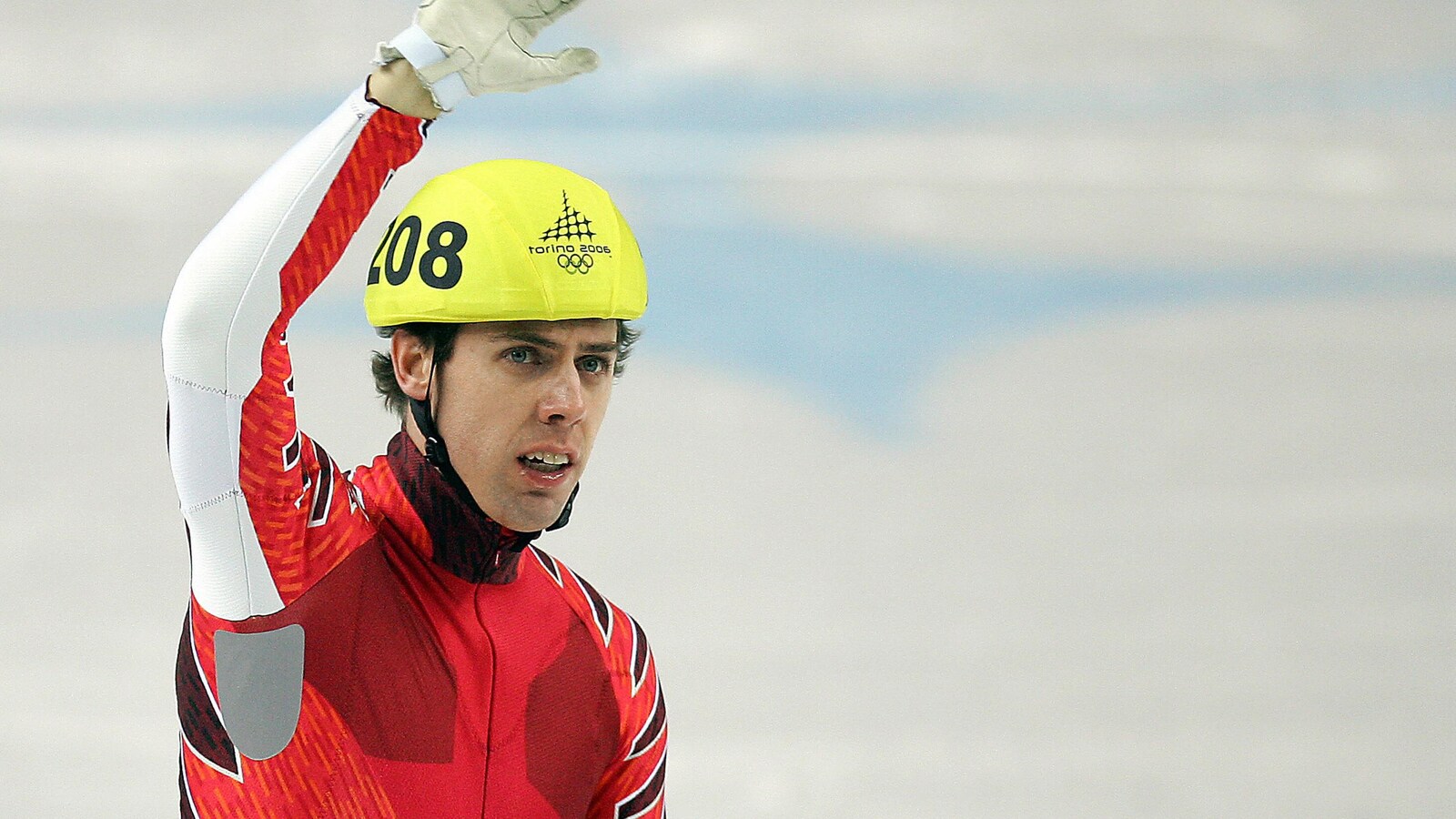 Éric Bédard, dans sa combinaison de patinage, salue la foule de la main aux Jeux olympiques de Turin, en 2006