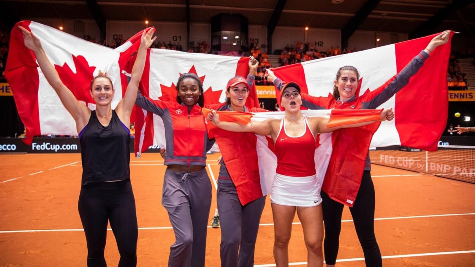 Les Canadiennes Gabriela Dabrowski, Heidi El Tabakh (capitaine), Françoise Abanda, Bianca Andreescu et Rebecca Marino célèbrent leur victoire contre les Pays-Bas avec des drapeaux canadiens alors qu'elles accèdent au barrage du groupe mondial, prévu les 20 et 21 avril prochains.