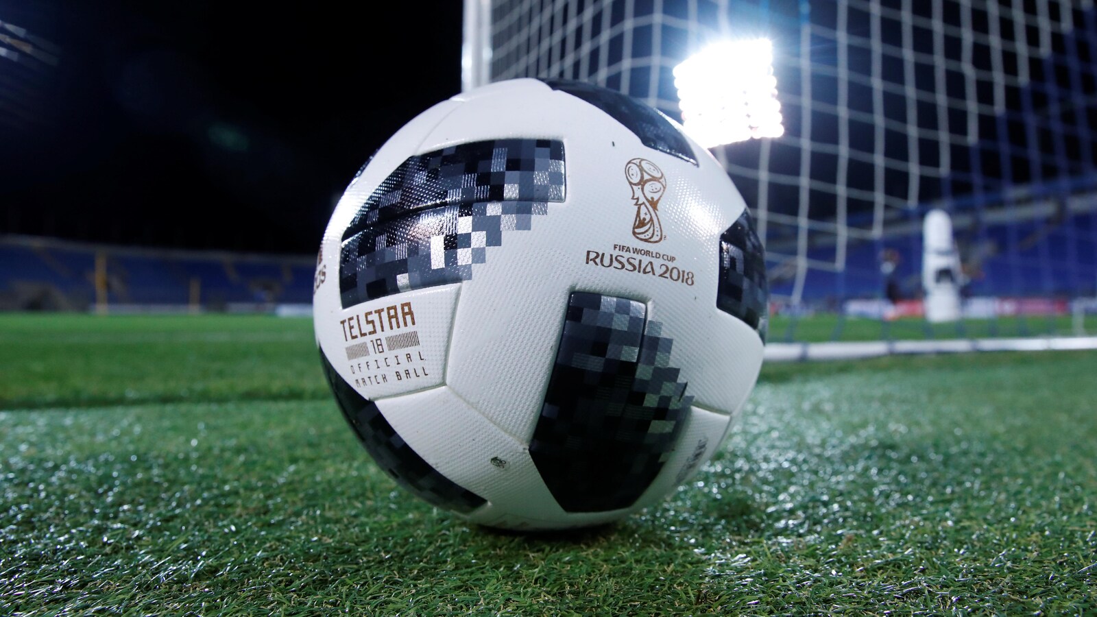 Le ballon est placé sur le gazon devant le but.