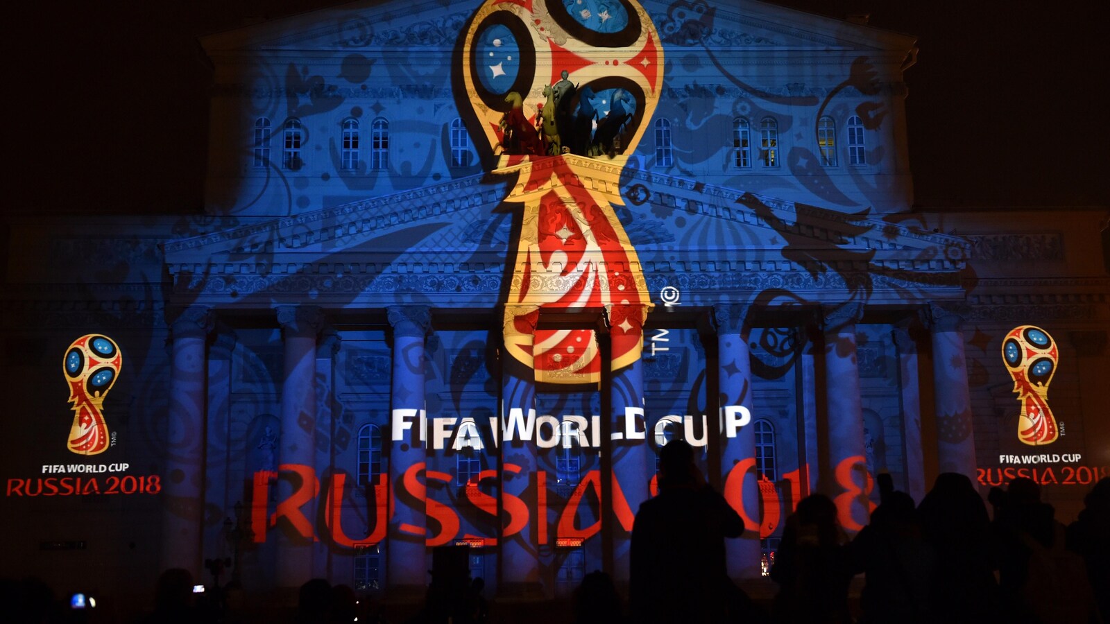 Des spectateurs observent la projection du logo officiel sur le théâtre Bolchoï à Moscou.