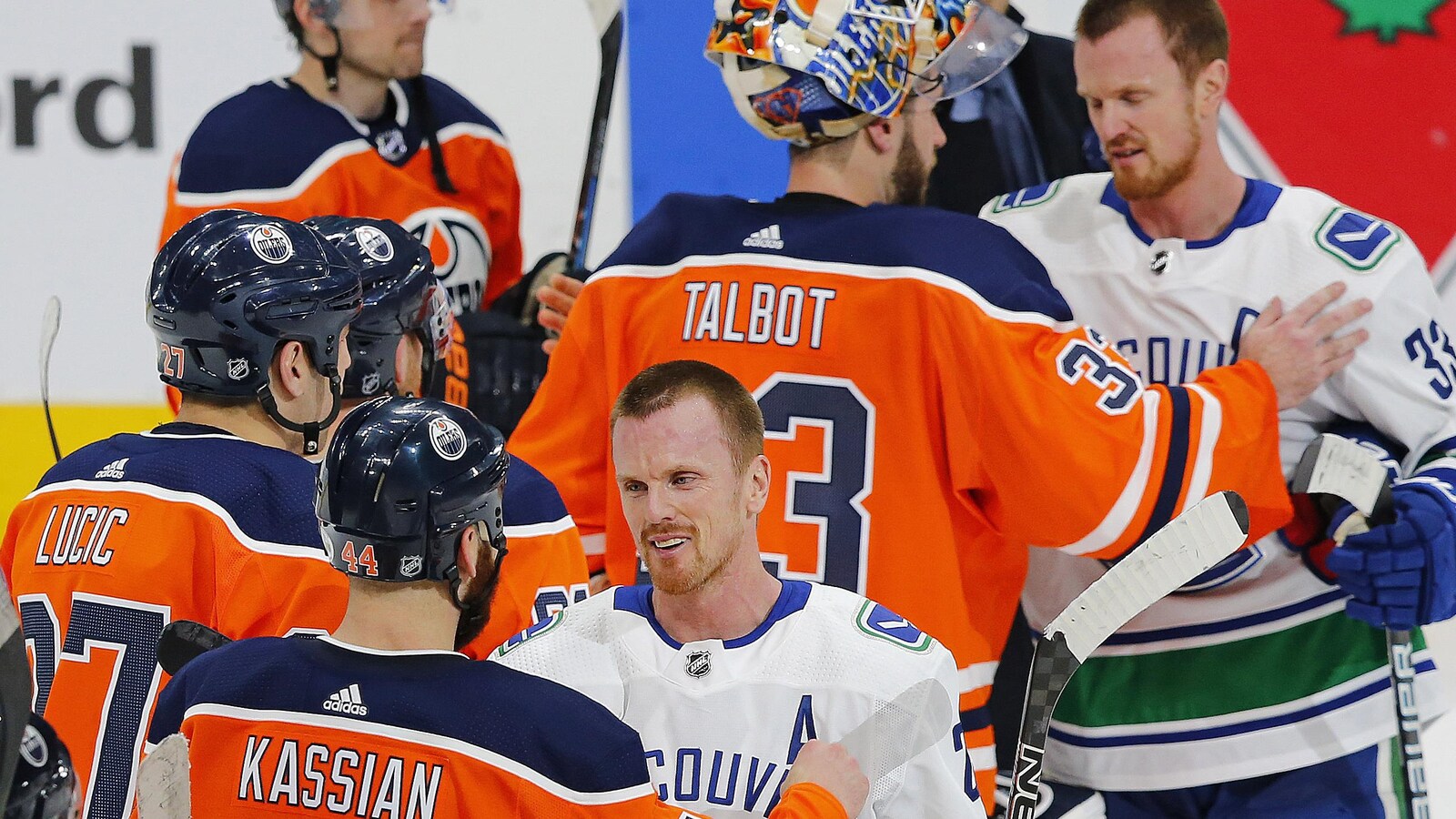Daniel Sedin parle avec son ex-coéquipier Zack Kassian. Derrière lui, Henrik s'entretien avec le gardien Cam Talbot.