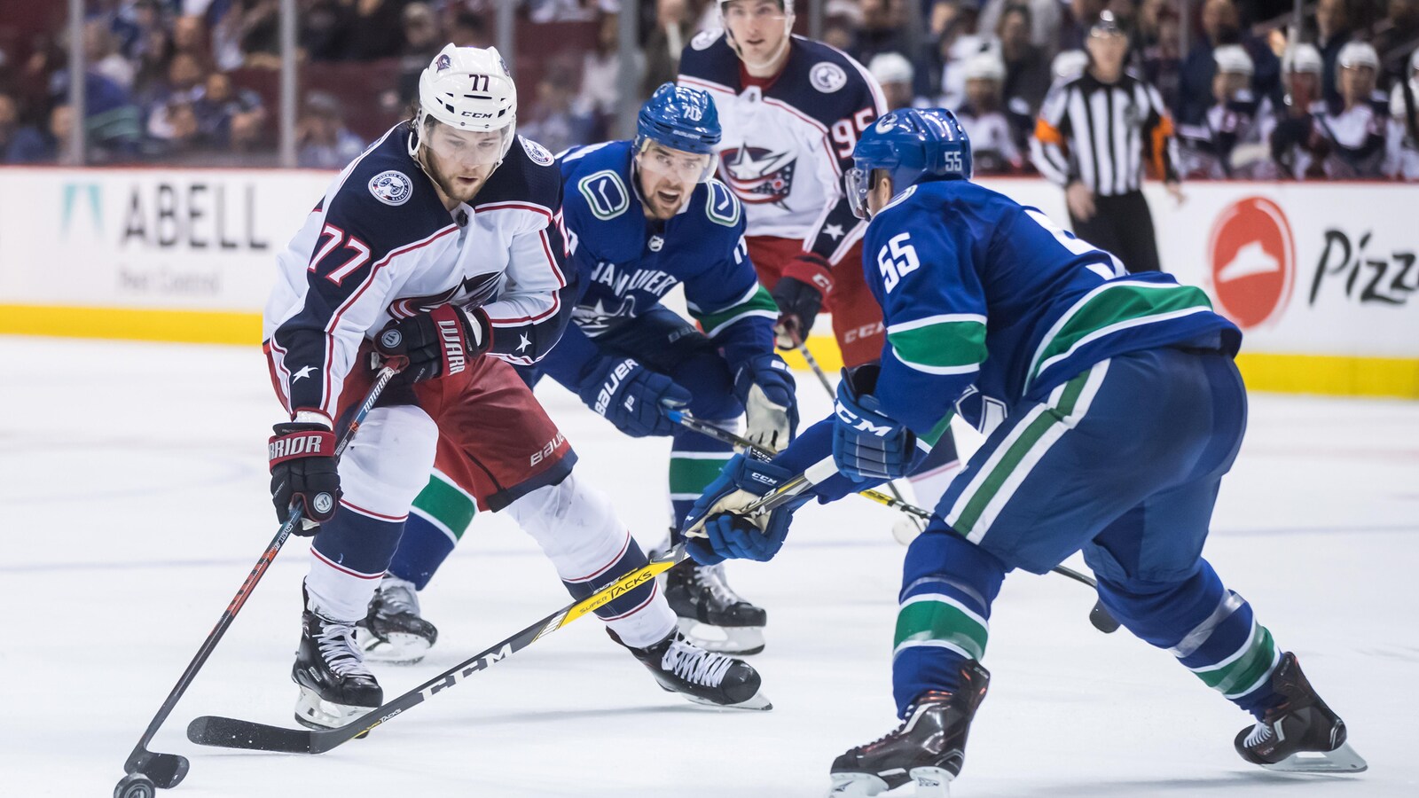 Josh Anderson (à gauche), des Blue Jackets de Columbus, maîtrise la rondelle devant Alex Biega (à droite), des Canucks de Vancouver.