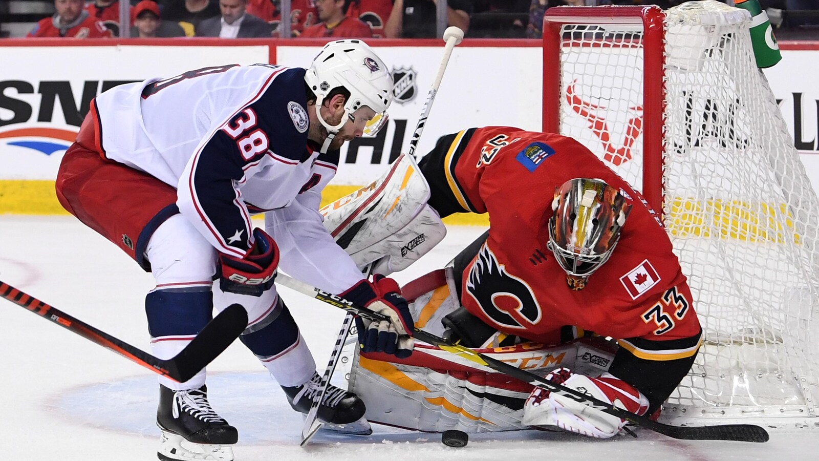 Le gardien David Rittich (à droite), des Flames de Calgary, stoppe un tir de Boone Jenner, des Blue Jackets de Columbus.