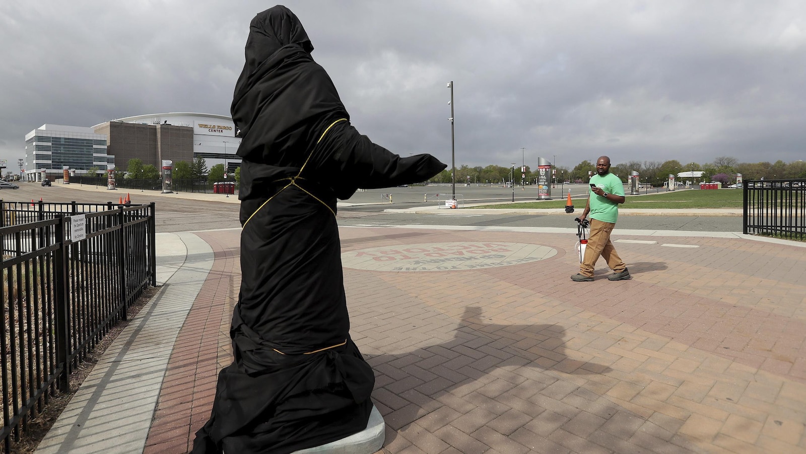 Un homme regarde la statue de Kate Smith, couverte d'une bâche, à l'extérieur du Wells Fargo Center.