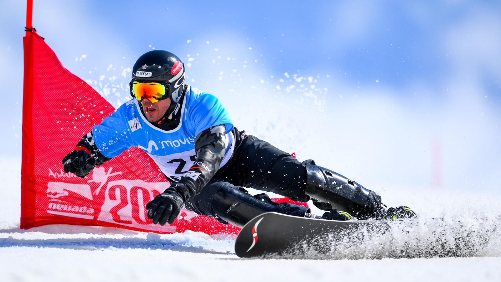 Le planchiste contourne un drapeau pendant une épreuve de slalom en surf des neiges.