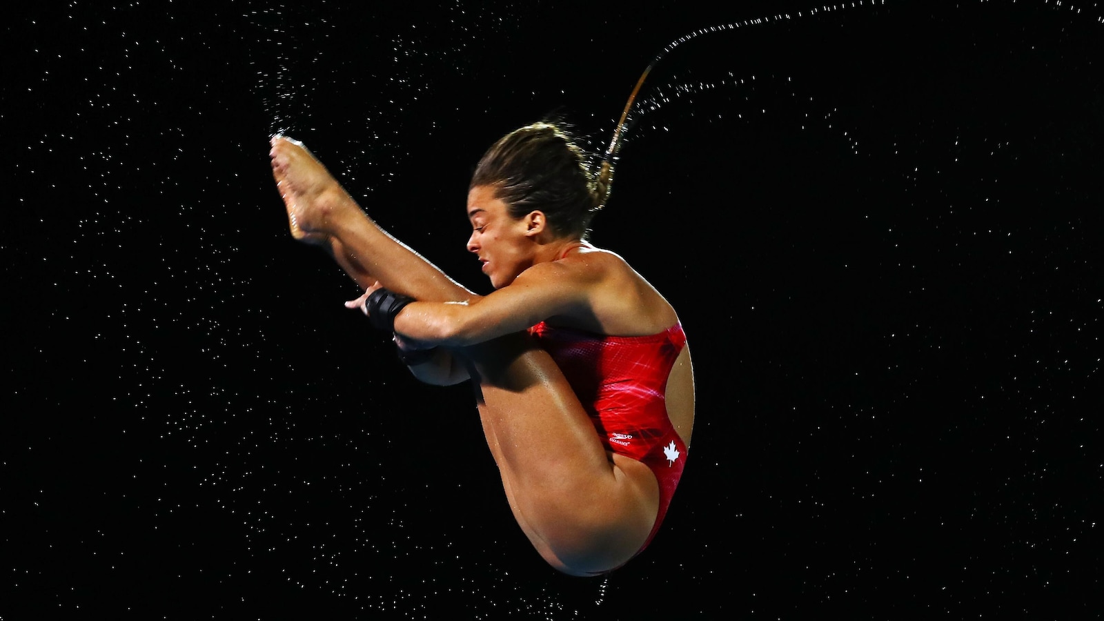 Elle effectue un plongeon en position carpée.