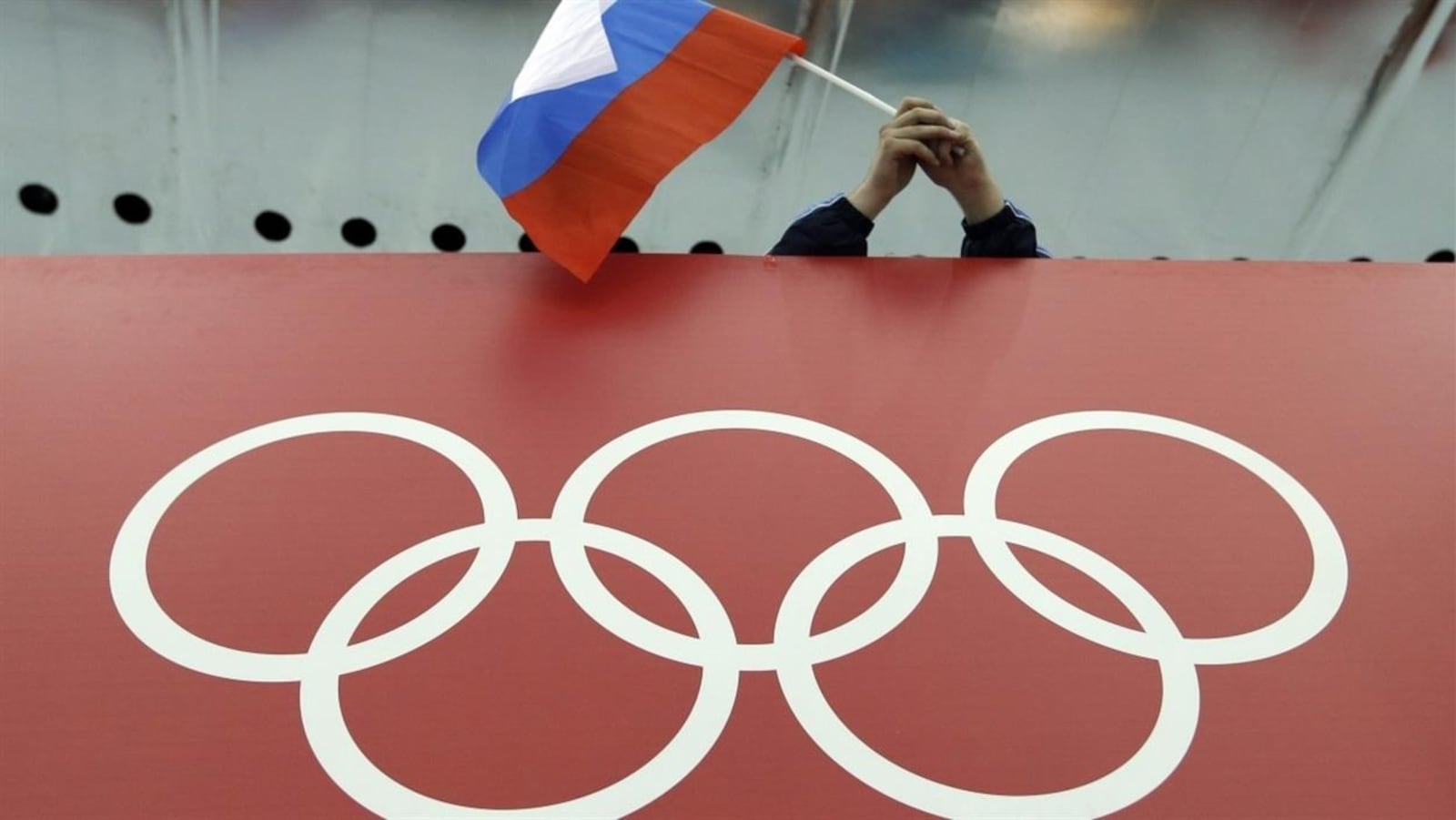 Un drapeau russe tenu au-dessus des anneaux olympiques.