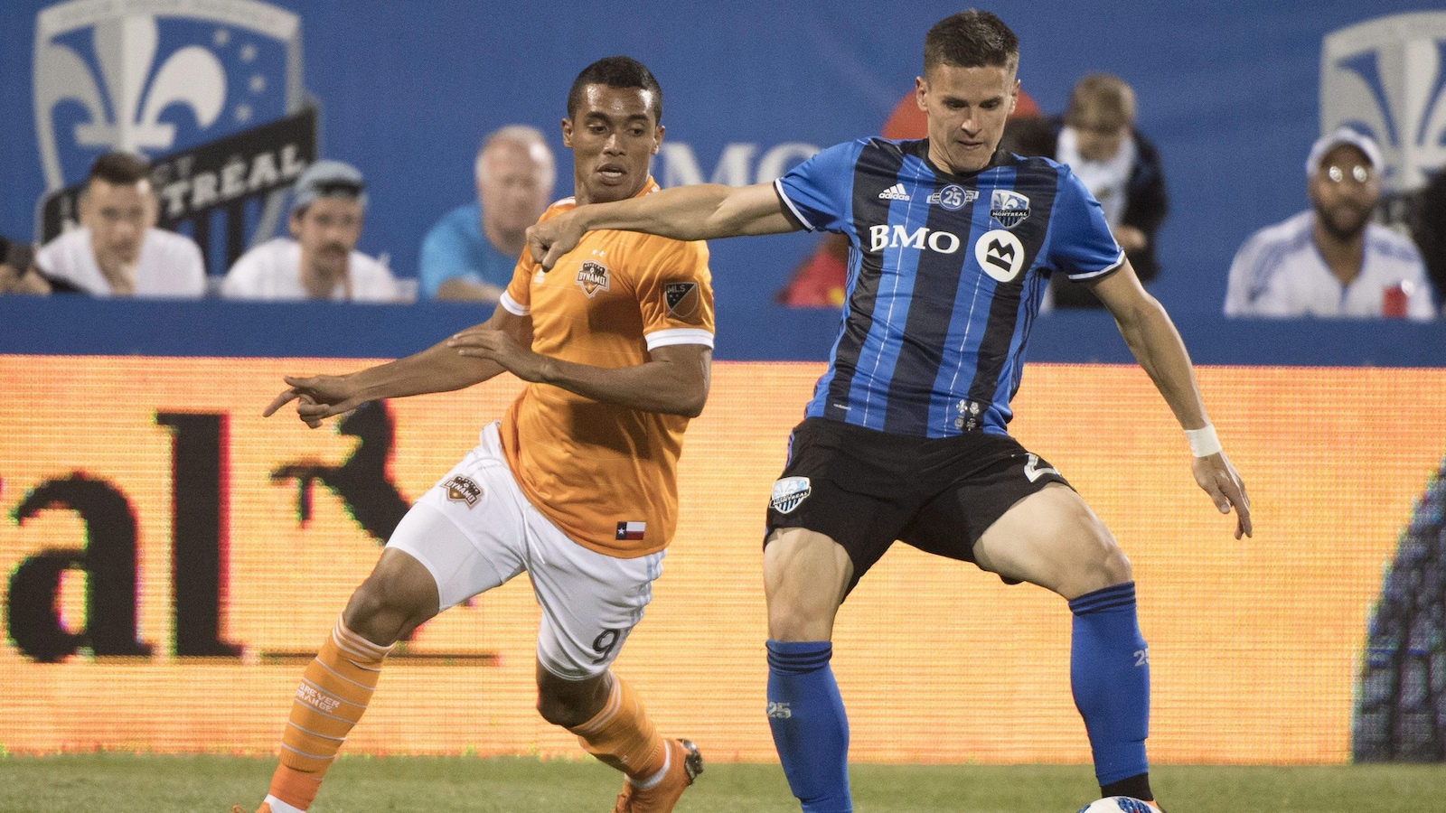 Le défenseur de l'Impact tente le joueur du Dynamo de Houston de prendre le ballon.