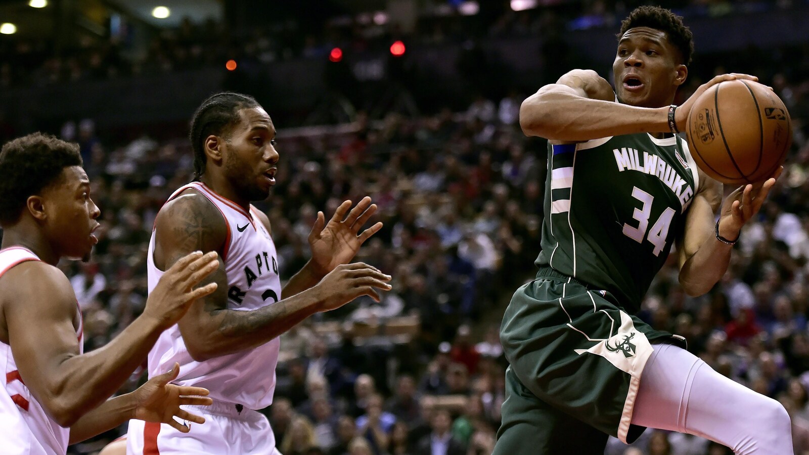 Giannis Antetokounmpo des Bucks de Milwaukee cherche une ligne de passe devant Kyle Lowry et Kawhi Leonard des Raptors de Toronto.